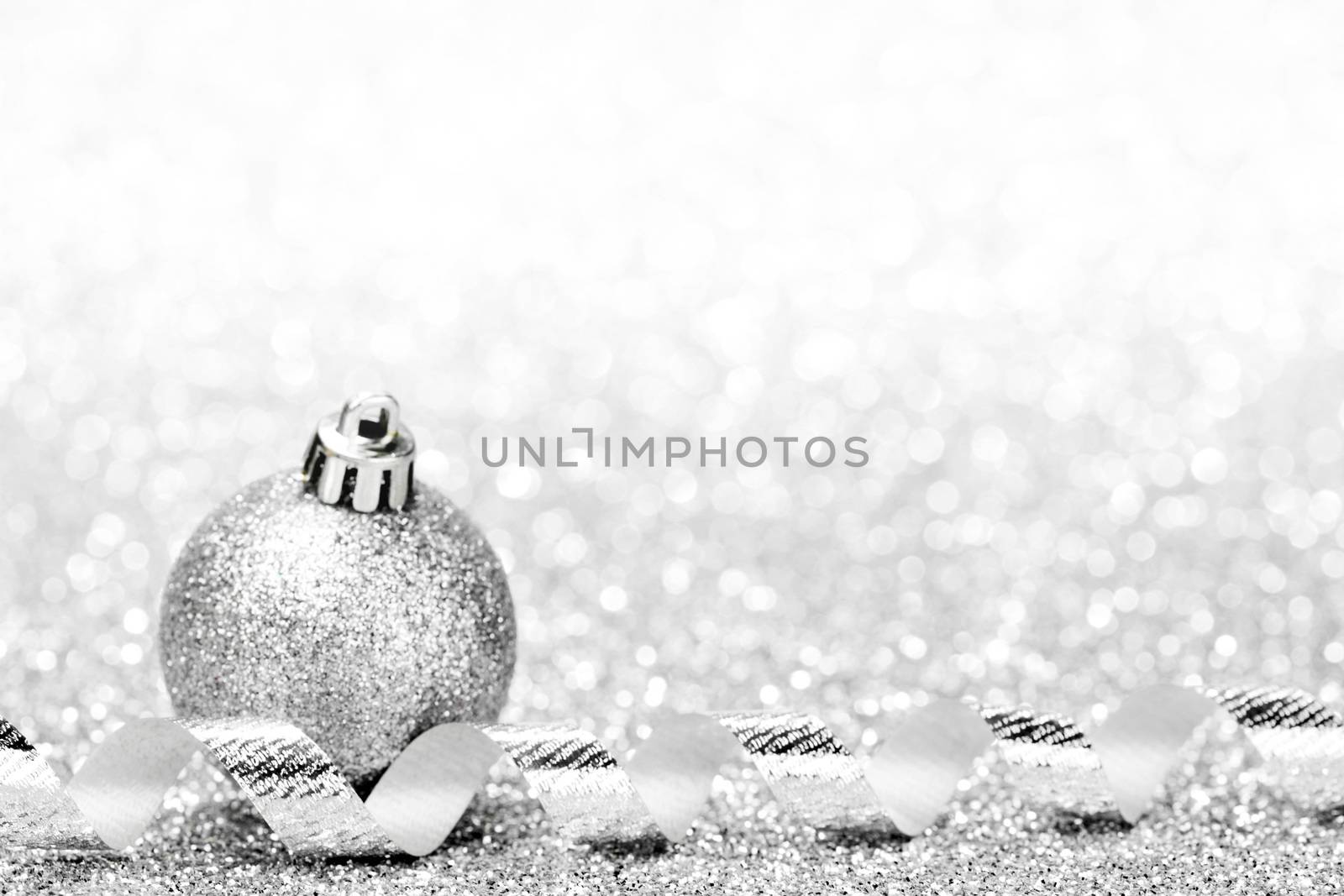 Christmas ball and curly decorative ribbon on bokeh background
