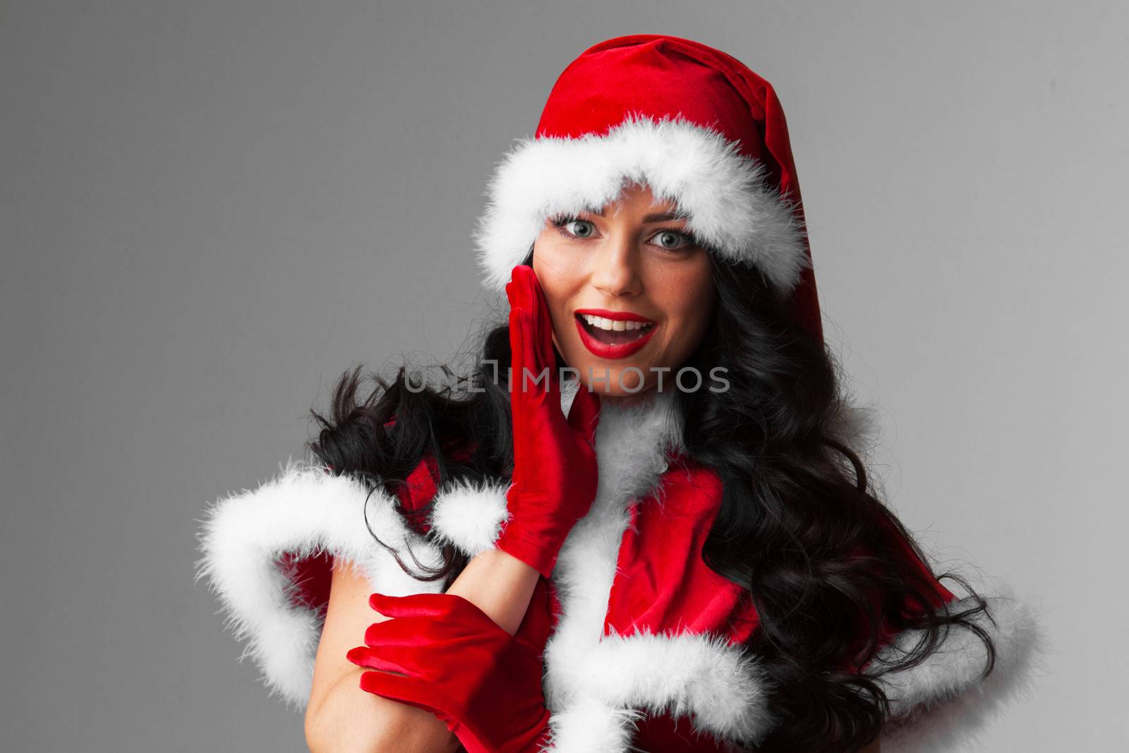 Pretty Pin-up style Santa girl in red clothes on gray background