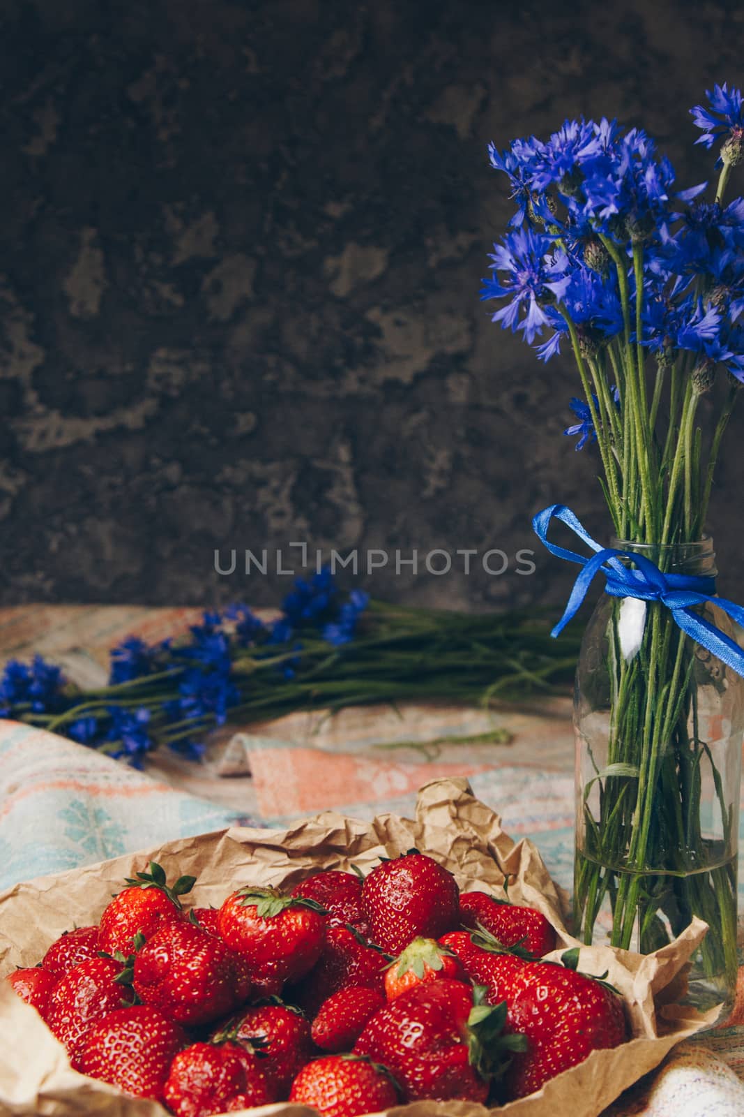 Seasonal summer flowers blue cornflowers and fruits strawberries on a napkin close-up conceptual background by yulaphotographer