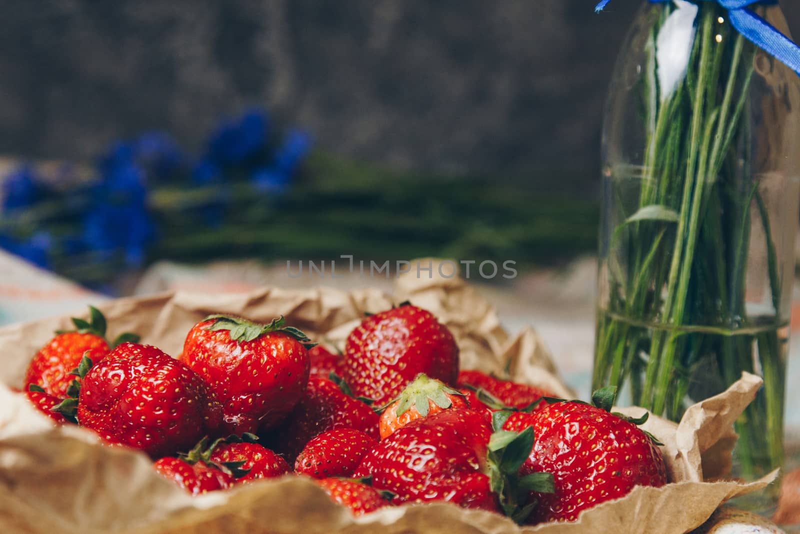 Seasonal summer flowers blue cornflowers and fruits strawberries on a napkin close-up conceptual background by yulaphotographer