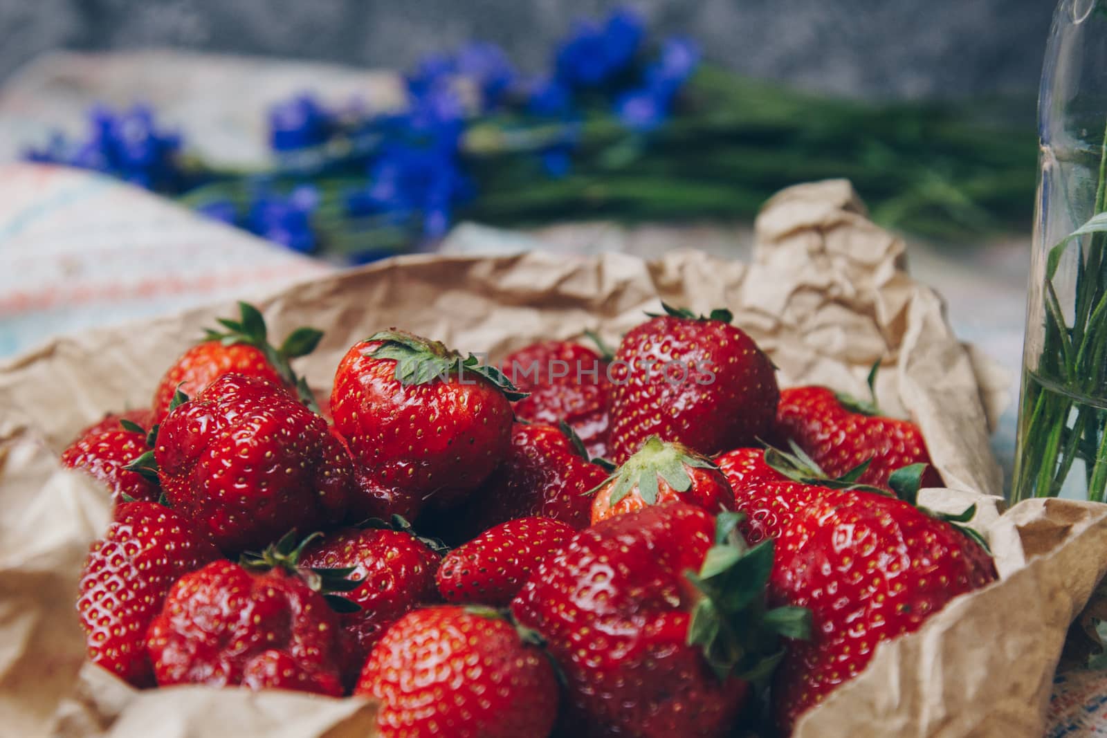 Seasonal summer flowers blue cornflowers and fruits strawberries on a napkin close-up conceptual background by yulaphotographer