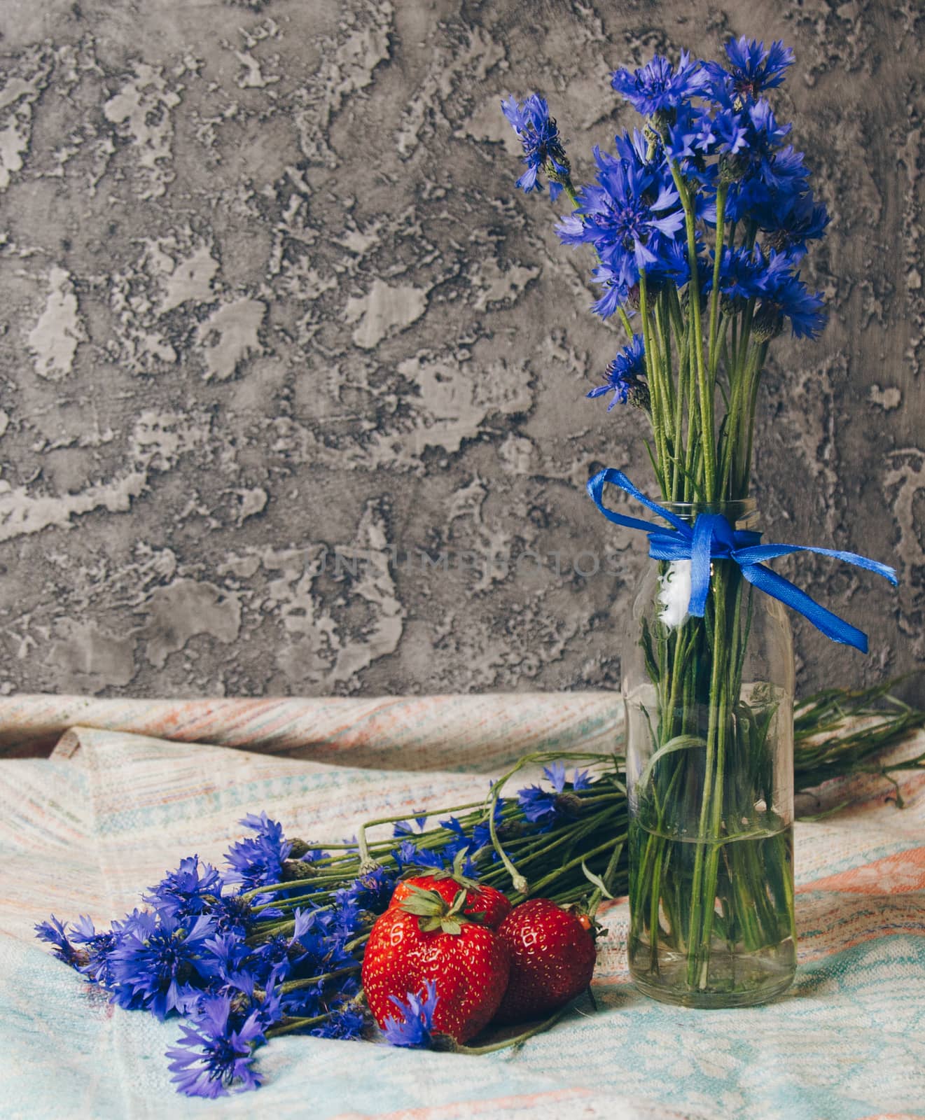 Seasonal summer flowers blue cornflowers and fruits strawberries on a napkin close-up conceptual background by yulaphotographer