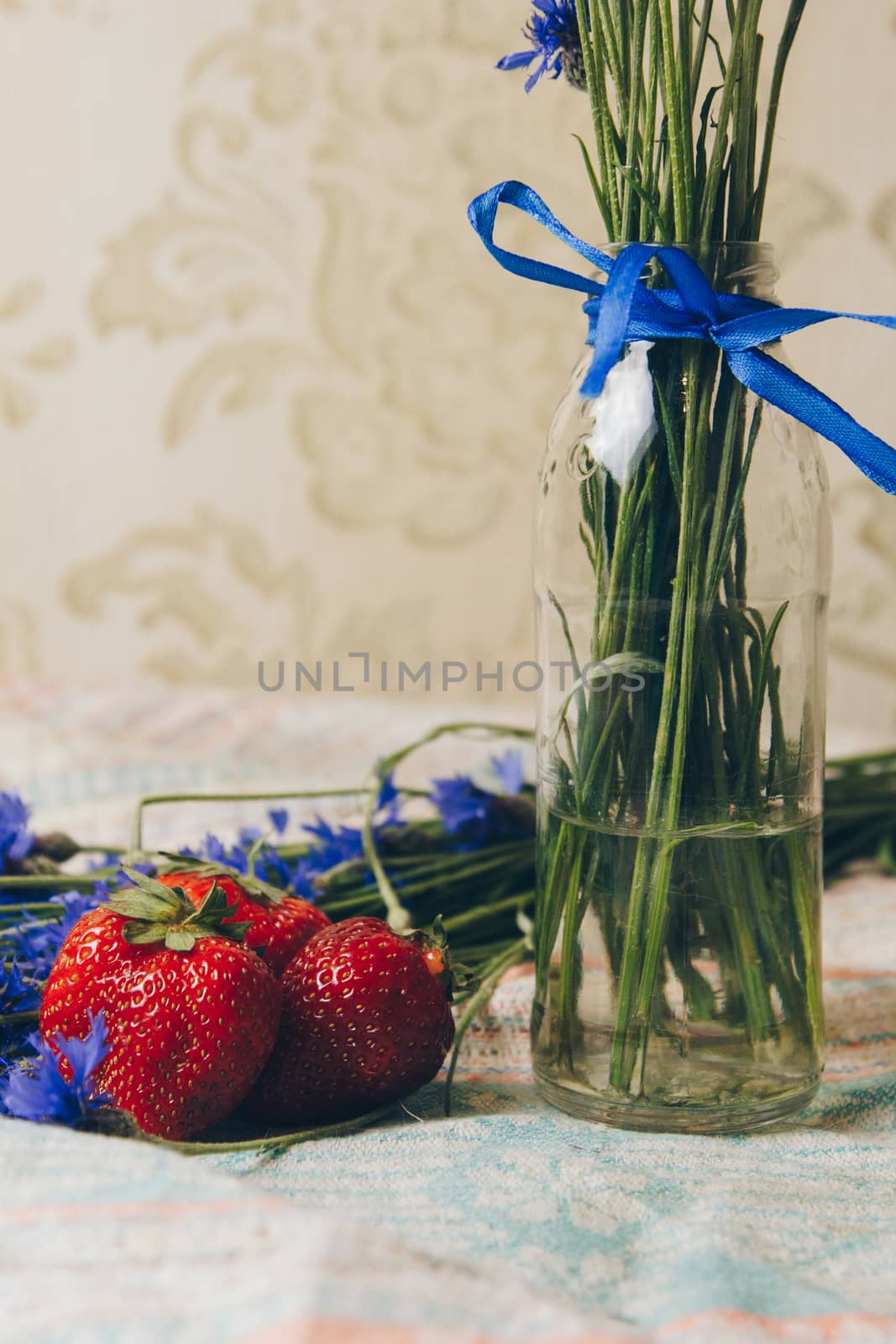 Seasonal summer flowers blue cornflowers and fruits strawberries on a napkin close-up conceptual background by yulaphotographer