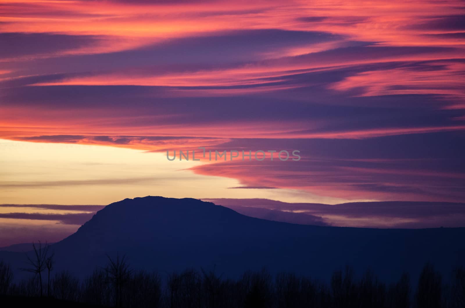Orange and purple fluffy clouds at sunset over Etxauri s peak at Navarra, Spain