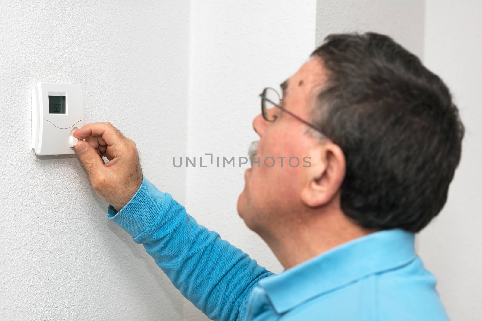 Man adjusting thermostat at home, focus on thermostat. Celsius temperature scale.