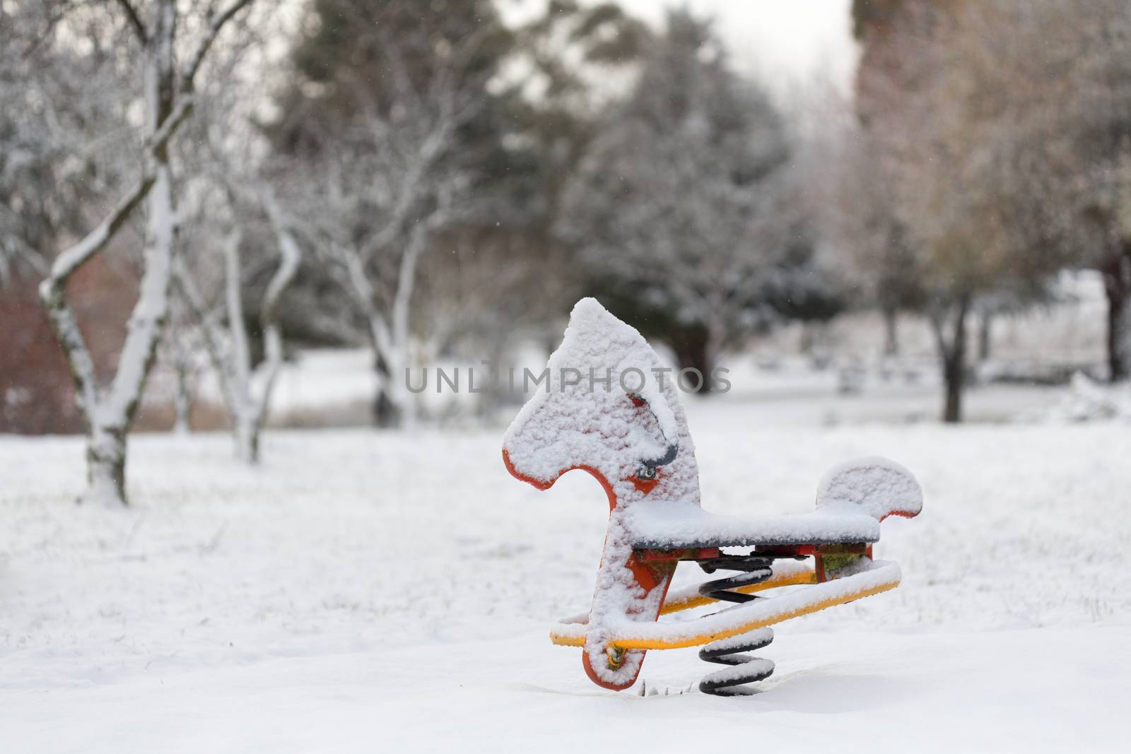 A bouncy rocking horse child's playground equipment covered in fresh snow in a park in Oberon rural Australia,  Very fine snow flakes falling