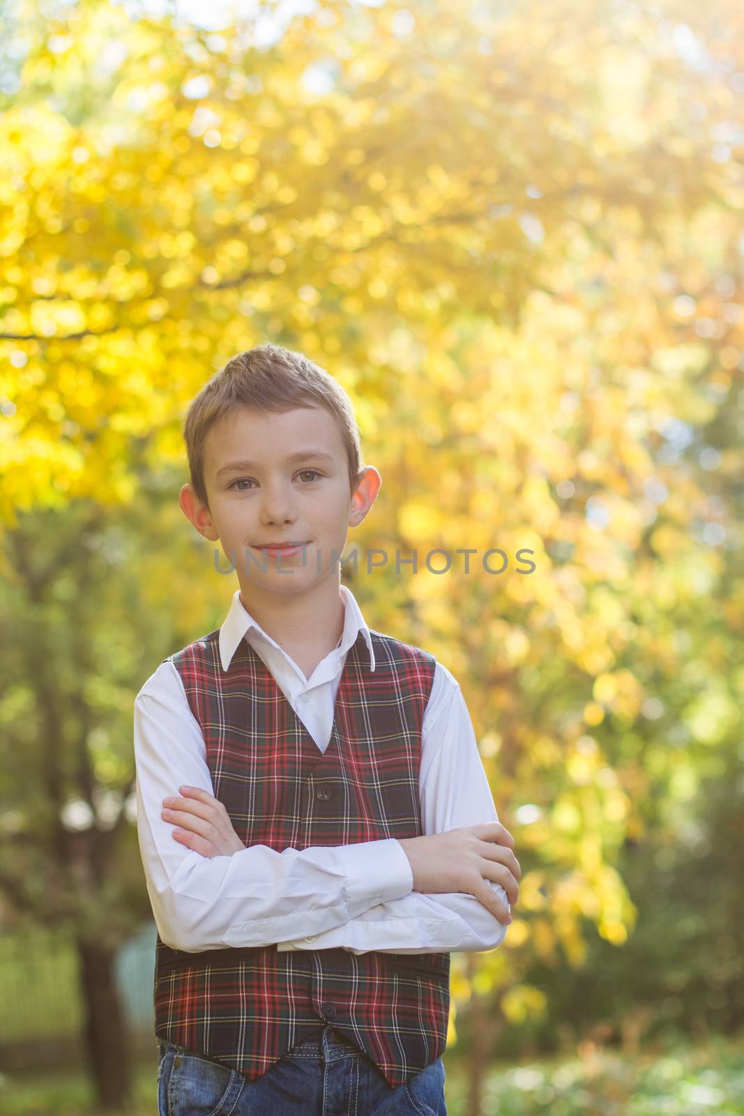 Schoolboy in uniform on autumn yellow background