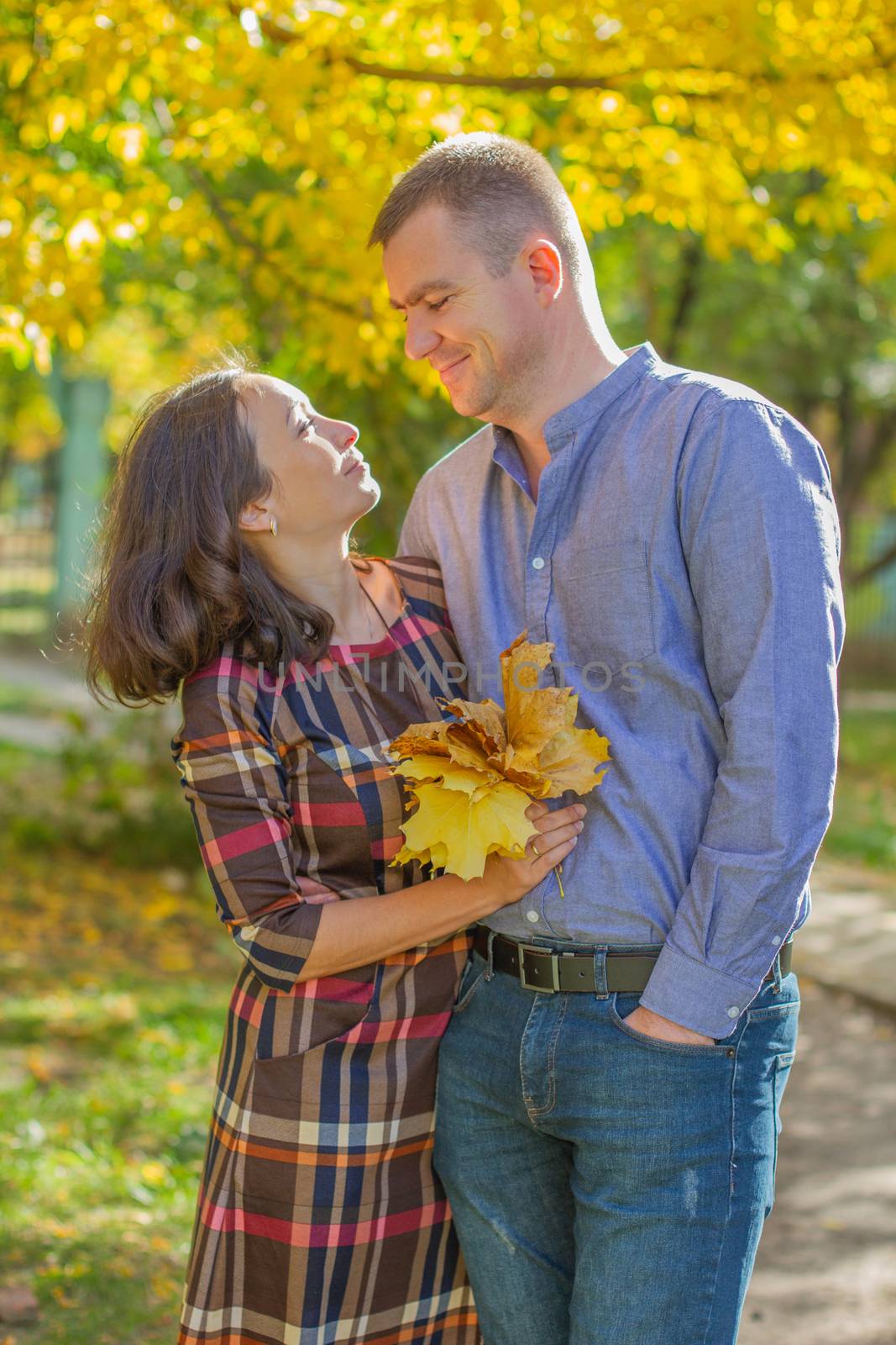 Loving couple hugging among yellow autumn trees