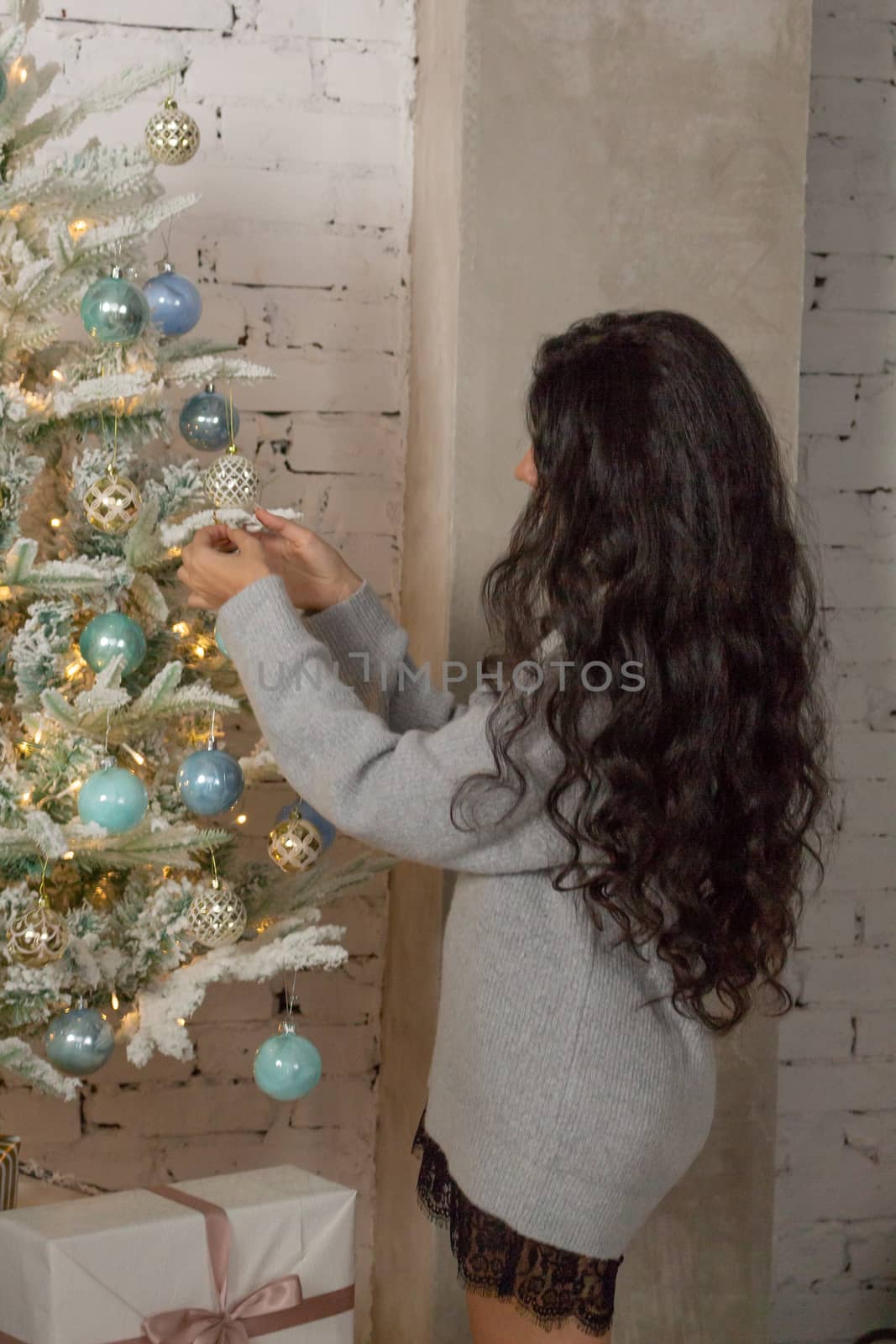 Girl decorates the Christmas tree. The view from the back.