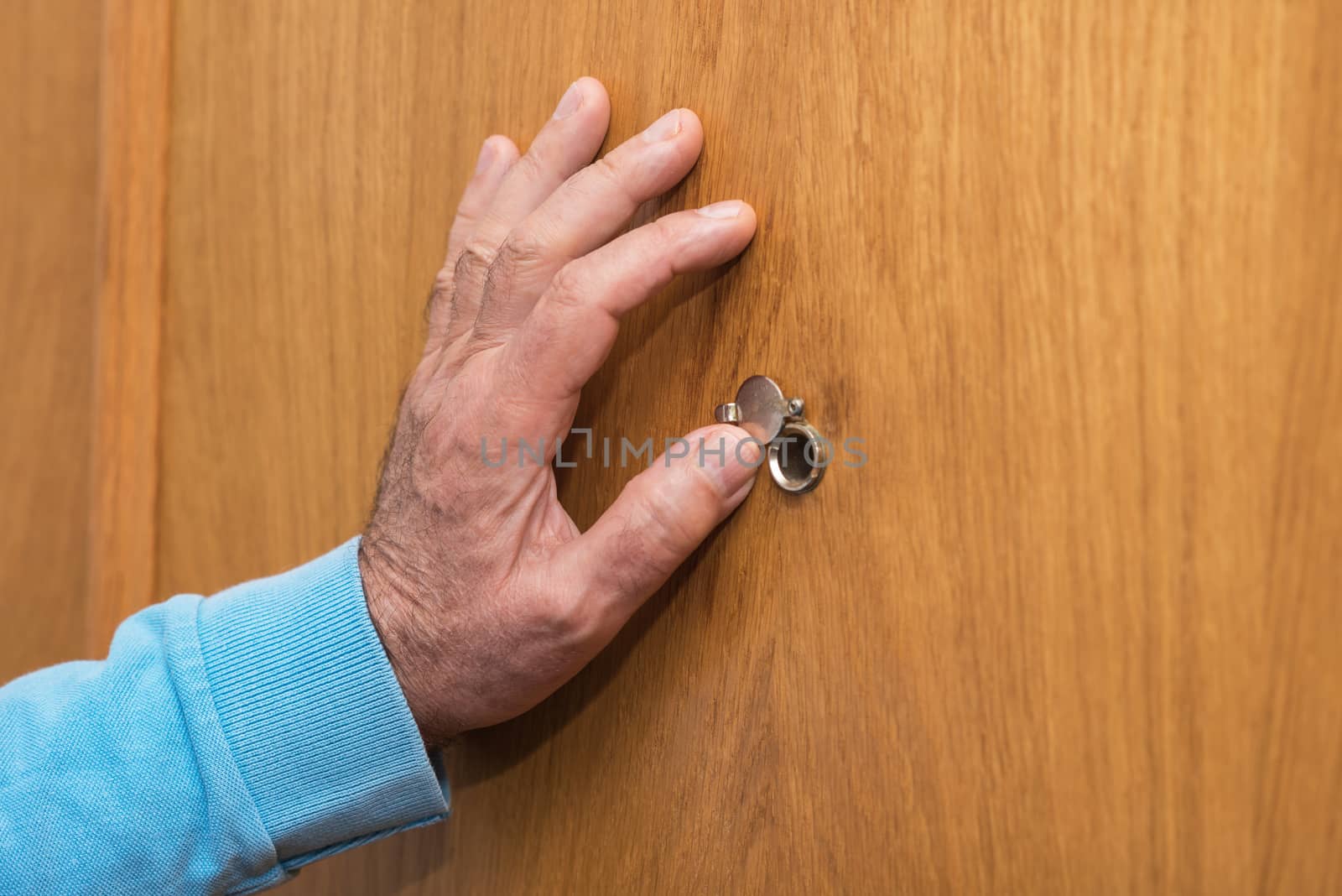 Senior man hand open the peephole cover door by HERRAEZ