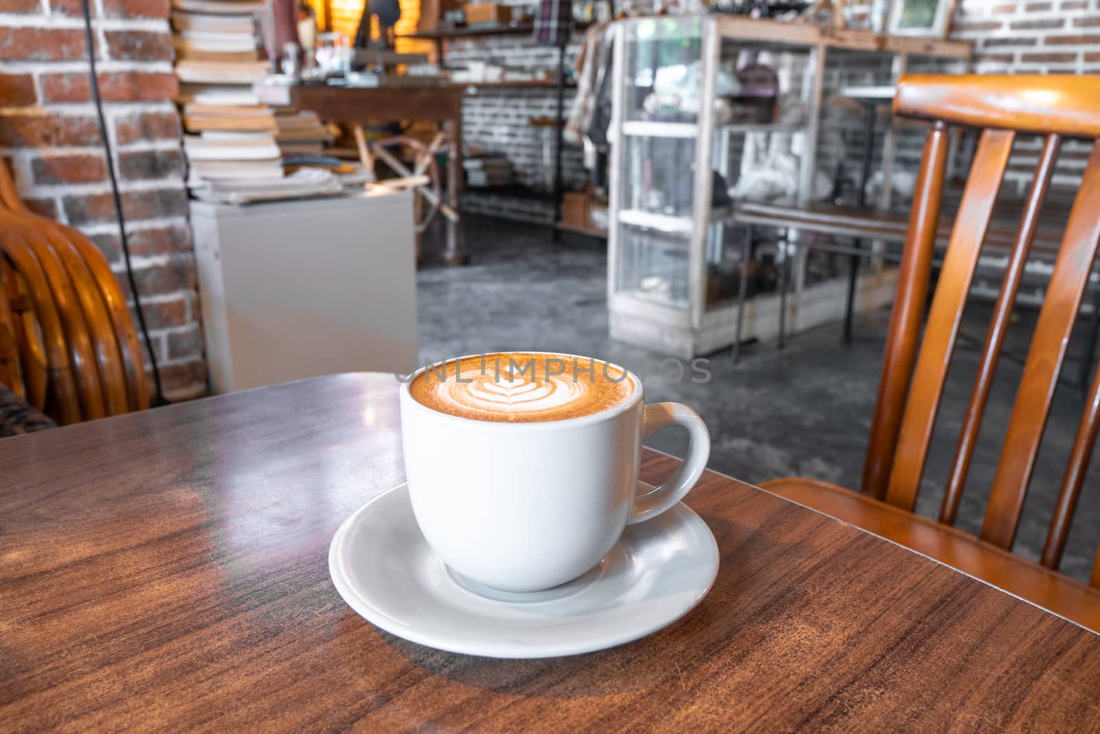 Coffee cup with milk and heart shape. Hot mocha coffee or capuchino in the white cup with heart pattern on the wooden table. by wittaya