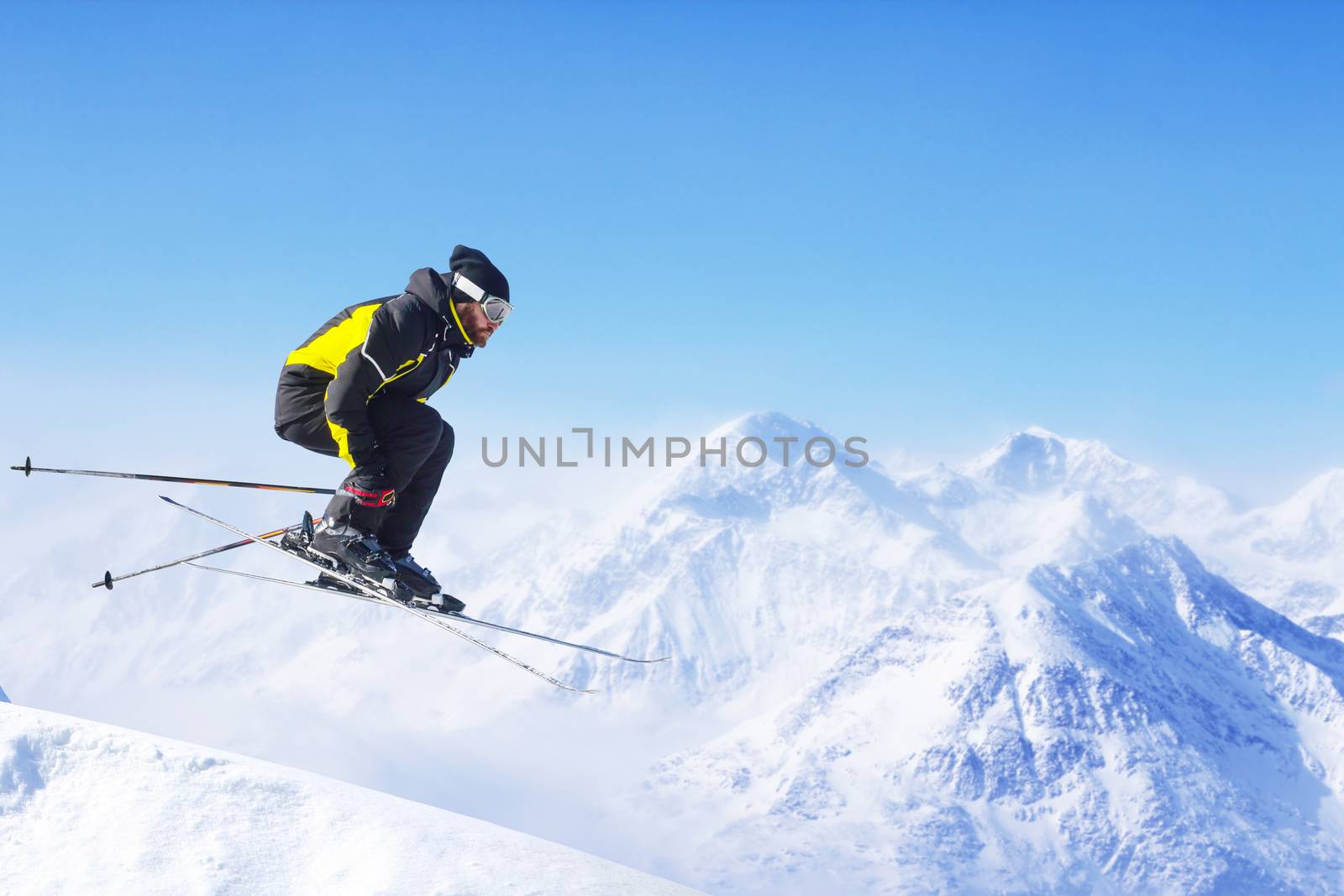 Jumping skier at jump with alpine high mountains
