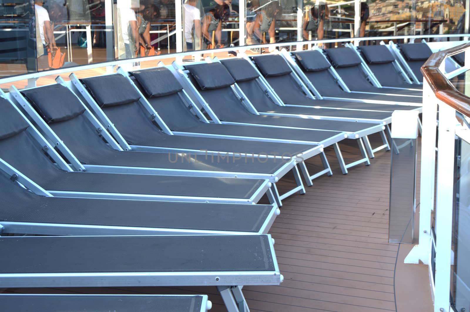 Empty sunbeds lounge chairs for relaxing on the open deck of a cruise ship.