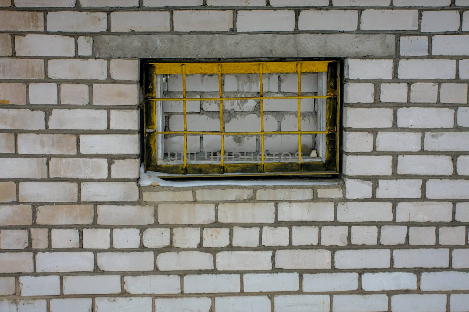 white brick wall with yellow grill in Cesis, Latvia.