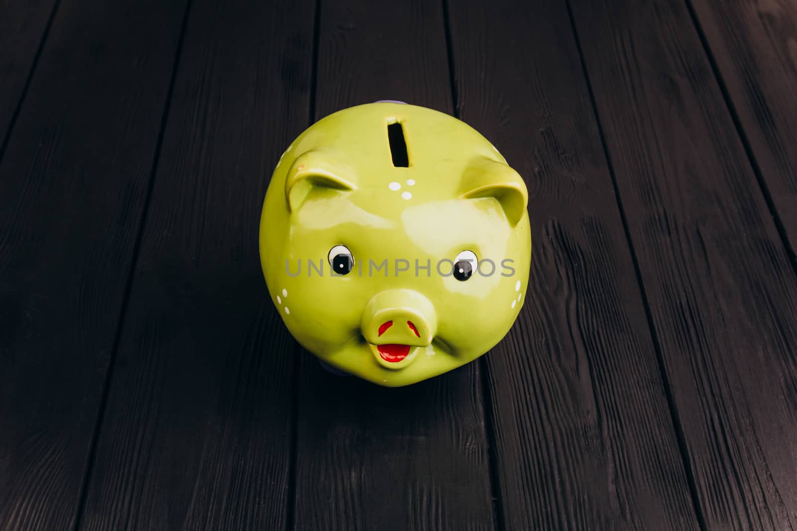 Cute smiling green Piggy Bank on the Wooden Table by yulaphotographer