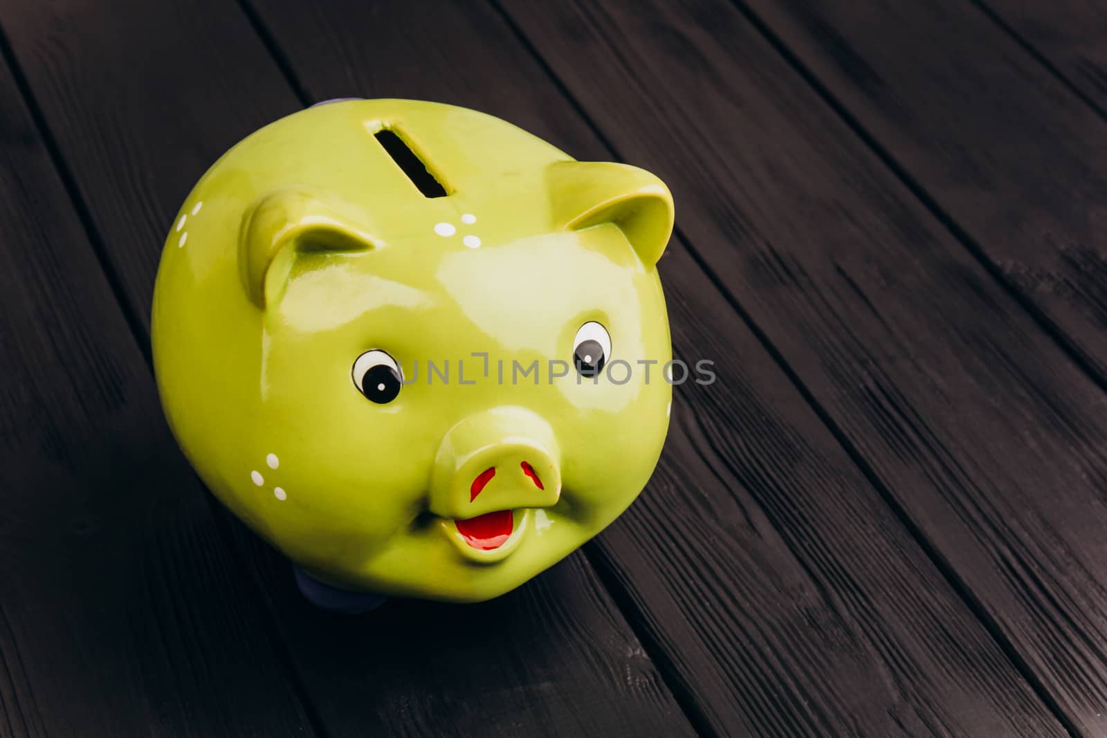 Cute smiling green Piggy Bank on the Wooden Table by yulaphotographer