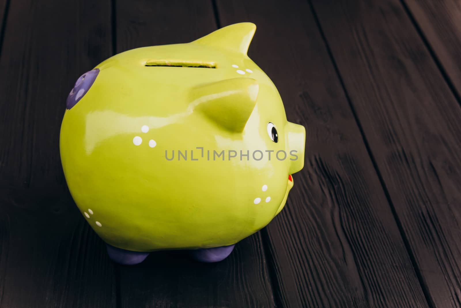 Cute smiling green Piggy Bank on the Wooden Table by yulaphotographer