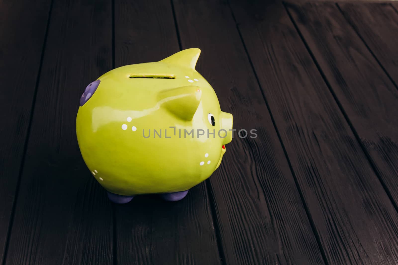 Cute smiling green Piggy Bank on the Wooden Table by yulaphotographer