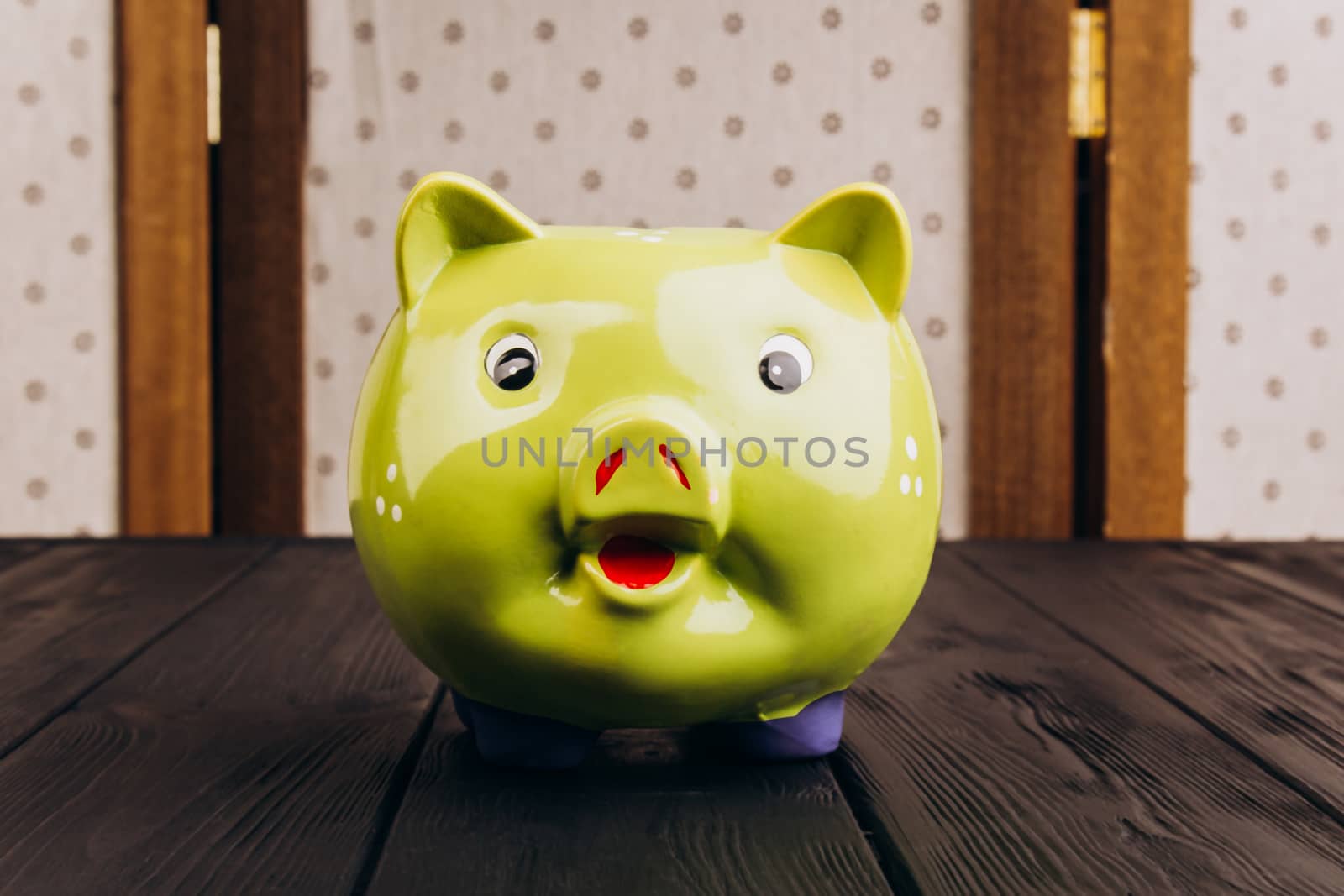 Cute smiling green Piggy Bank on the Wooden Table by yulaphotographer