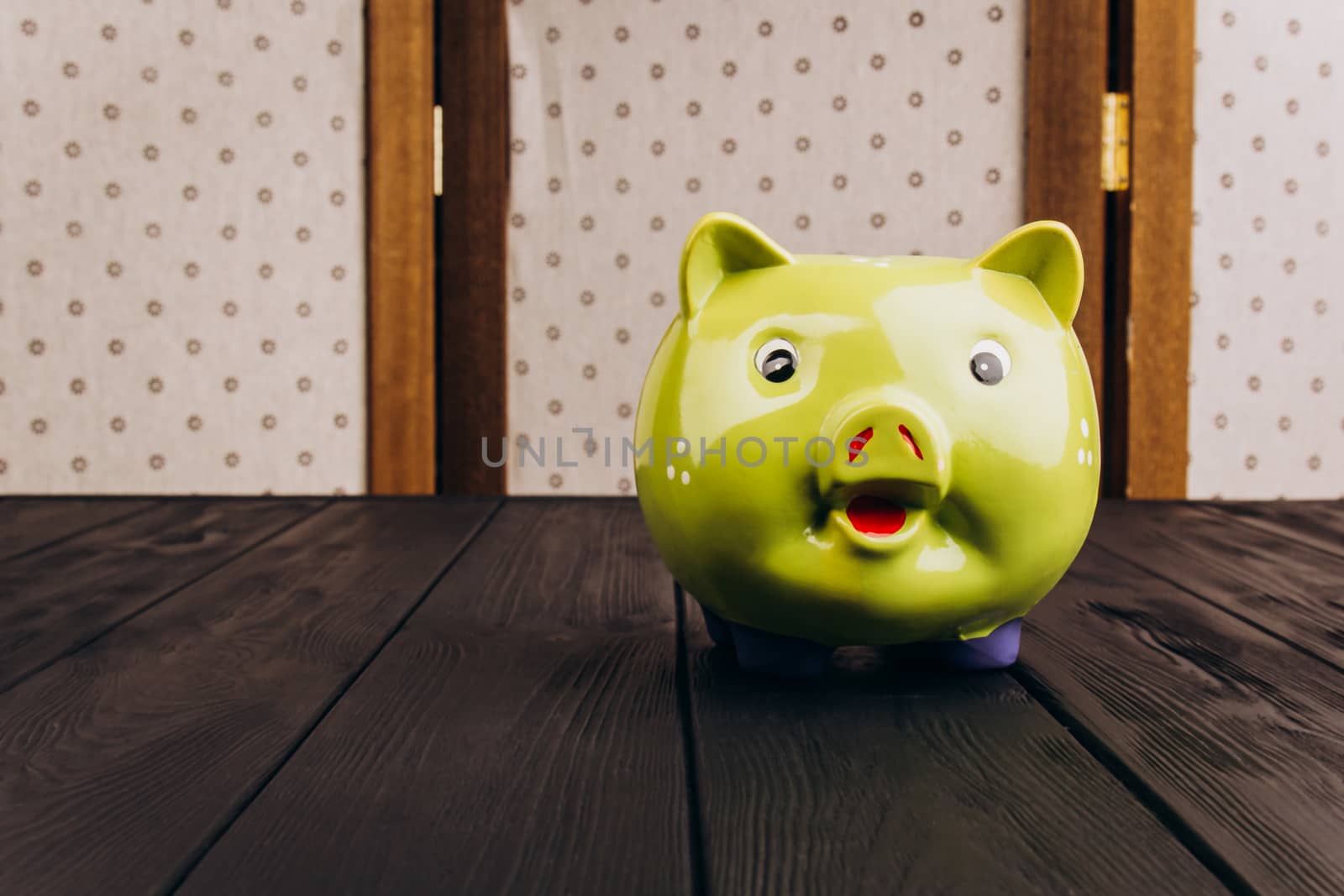 Cute smiling green Piggy Bank on the Wooden Table by yulaphotographer