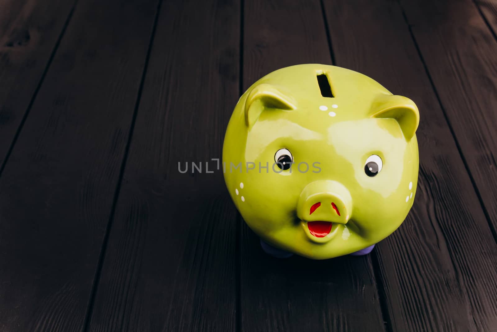 Cute smiling green Piggy Bank on the Wooden Table by yulaphotographer