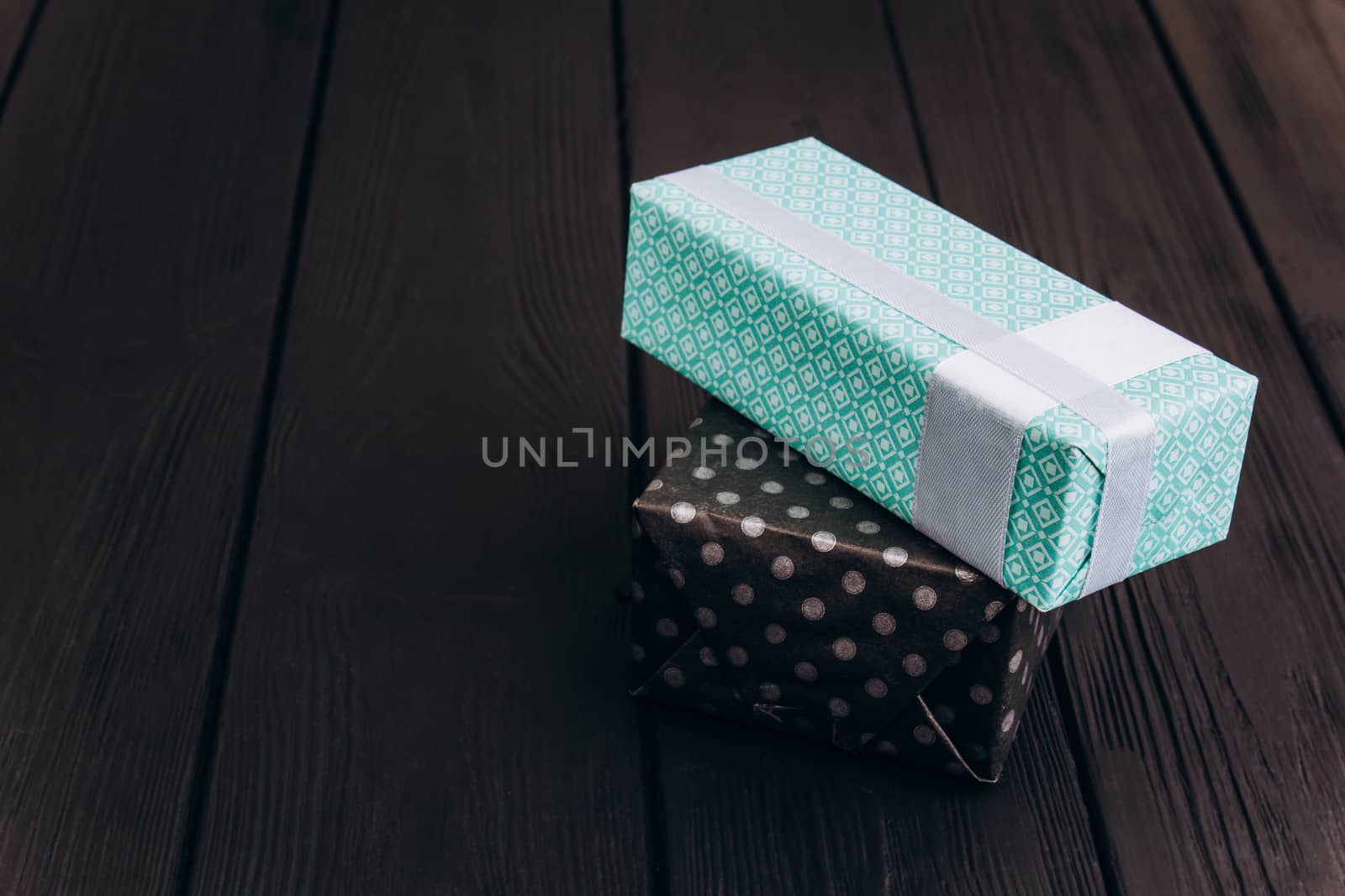 black and blue gift boxes on dark wood table background by yulaphotographer