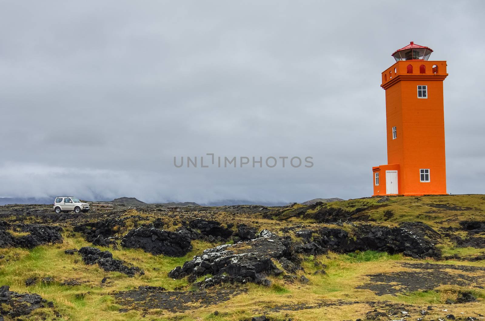 The car in front of orange lighthouse  on the rocks in Iceland, , Snaefellsnes Peninsulain