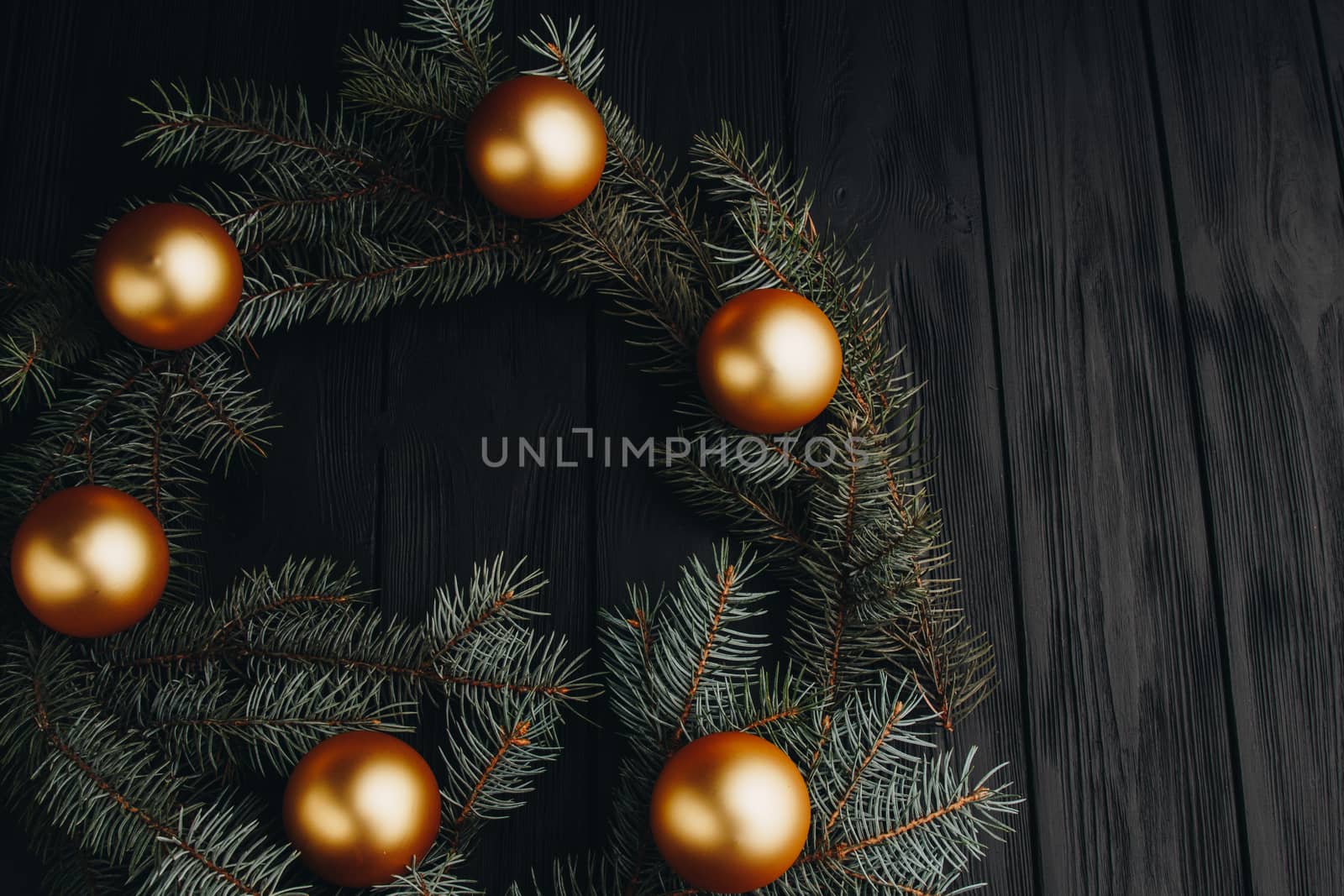 Christmas or New Year toy decorations golden balls and fur tree branch rustic on wooden background, top view, copy space by yulaphotographer