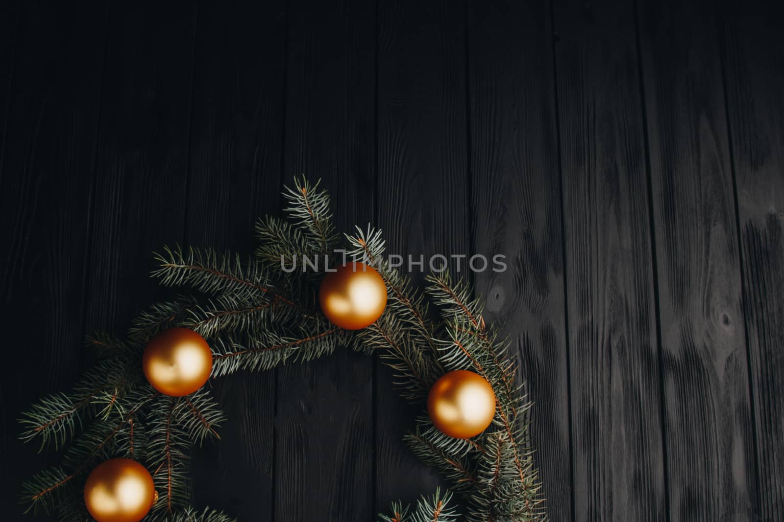 Christmas or New Year toy decorations golden balls and fur tree branch rustic on wooden background, top view, copy space by yulaphotographer