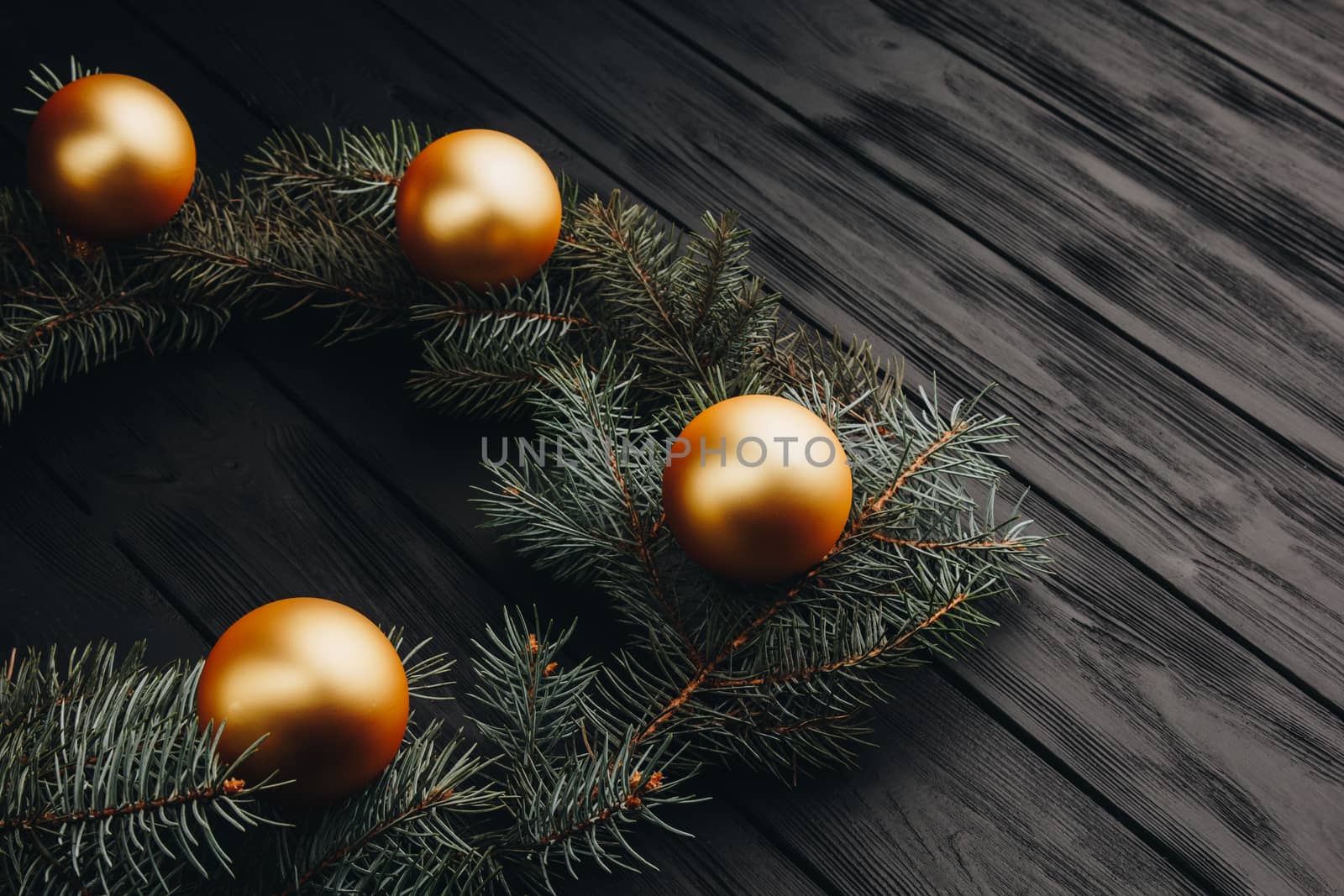 Christmas or New Year toy decorations golden balls and fur tree branch rustic on wooden background, top view, copy space by yulaphotographer