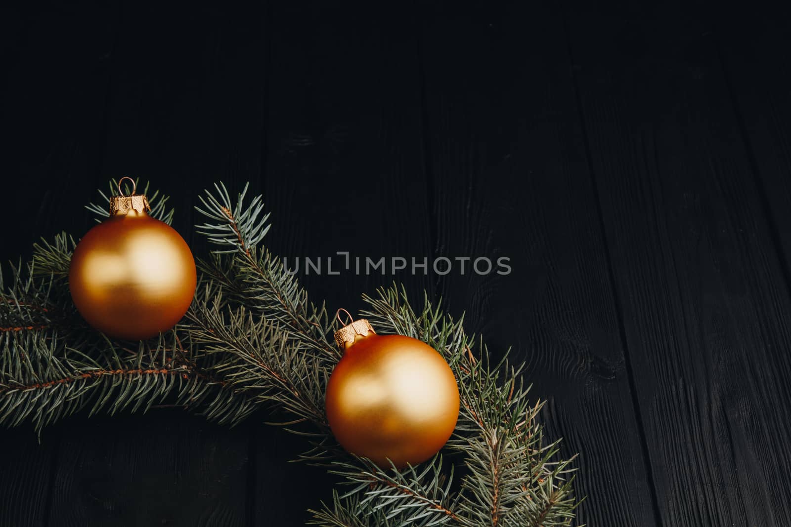 Christmas or New Year toy decorations golden balls and fur tree branch rustic on wooden background, top view, copy space by yulaphotographer