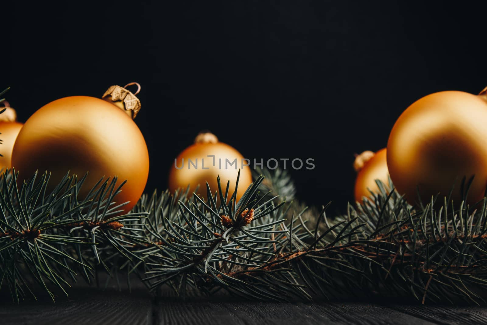 Christmas or New Year toy decorations golden ball and fur tree branch rustic on wooden background, top view, copy space