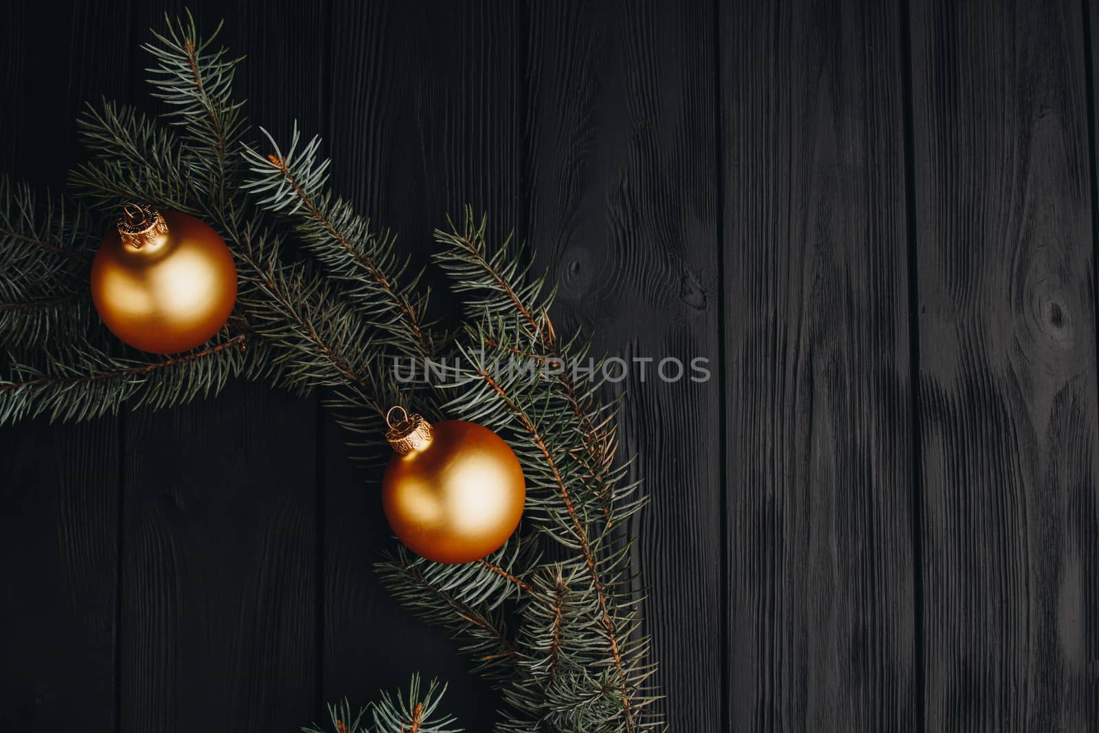 Christmas or New Year toy decorations golden balls and fur tree branch rustic on wooden background, top view, copy space by yulaphotographer