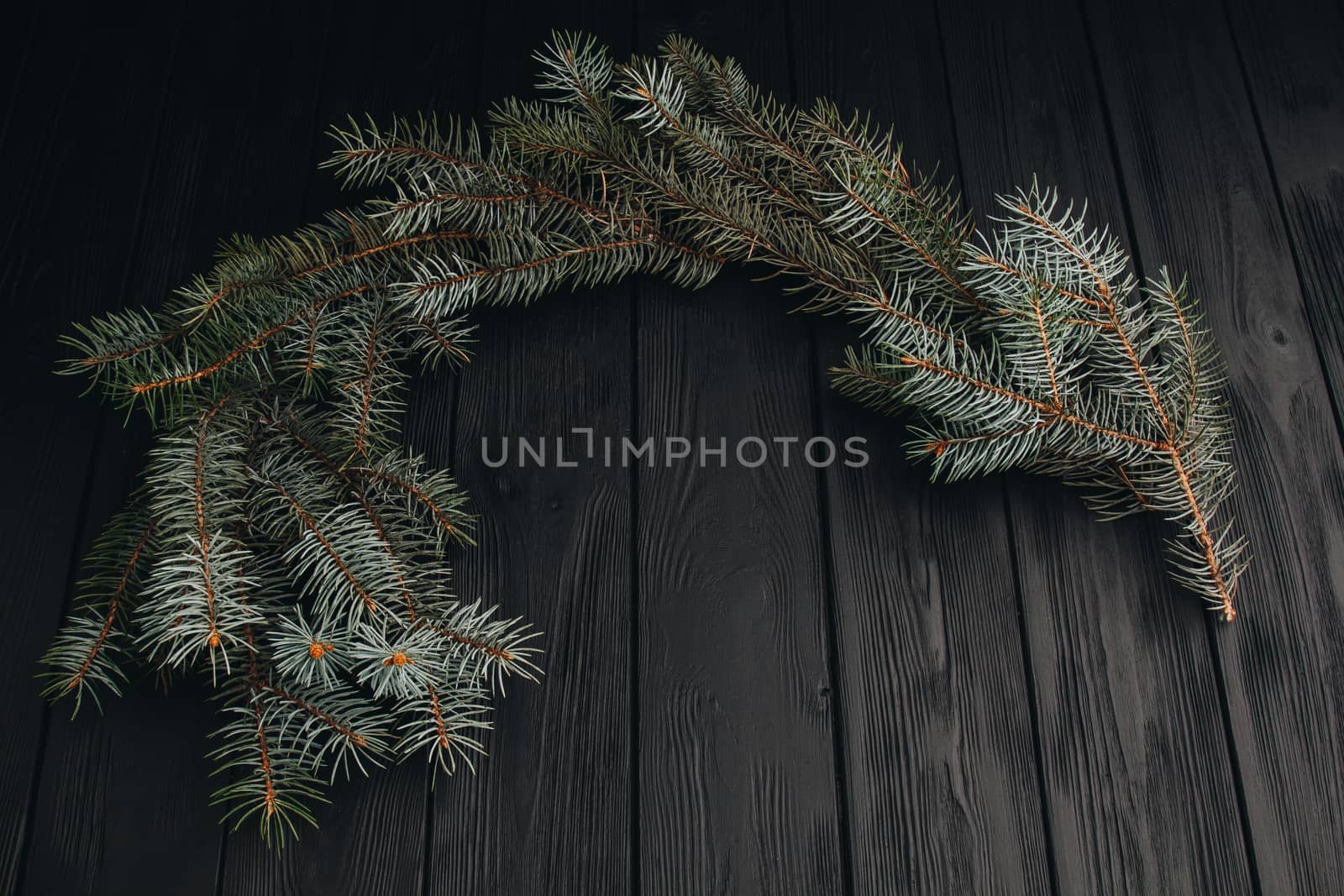 Christmas or New Year toy decorations golden balls and fur tree branch rustic on wooden background, top view, copy space by yulaphotographer