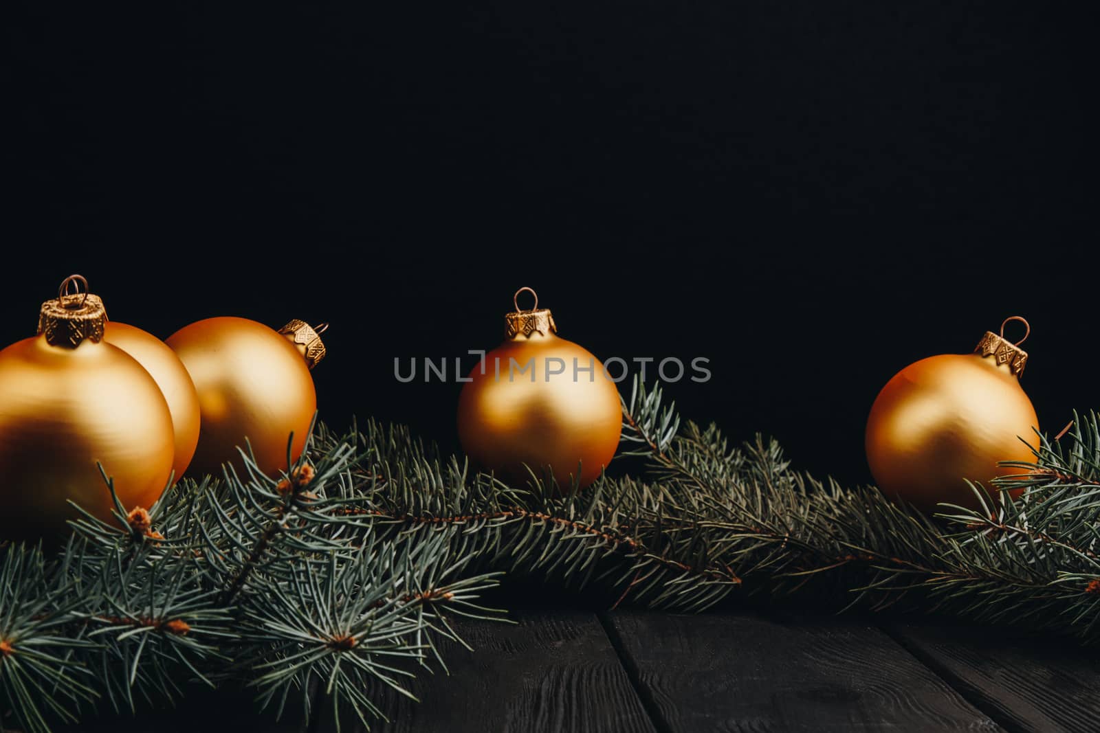 Christmas or New Year toy decorations golden balls and fur tree branch rustic on wooden background, top view, copy space by yulaphotographer