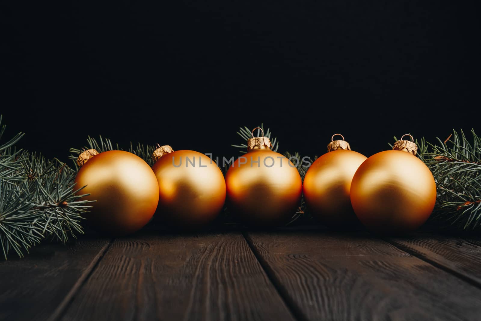 Christmas or New Year toy decorations golden balls and fur tree branch rustic on wooden background, top view, copy space by yulaphotographer