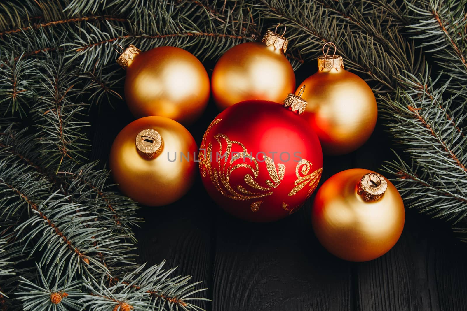 Christmas or New Year toy decorations golden balls and fur tree branch rustic on wooden background, top view, copy space by yulaphotographer