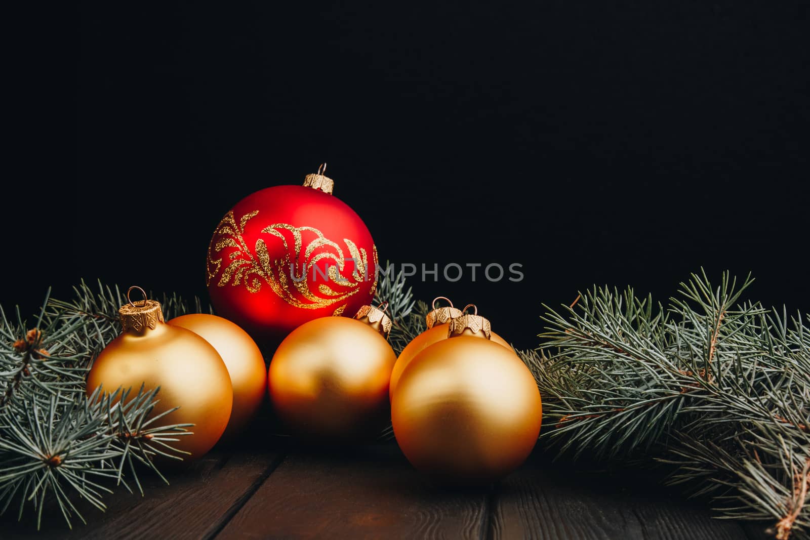 Christmas or New Year toy decorations golden balls and fur tree branch rustic on wooden background, top view, copy space by yulaphotographer