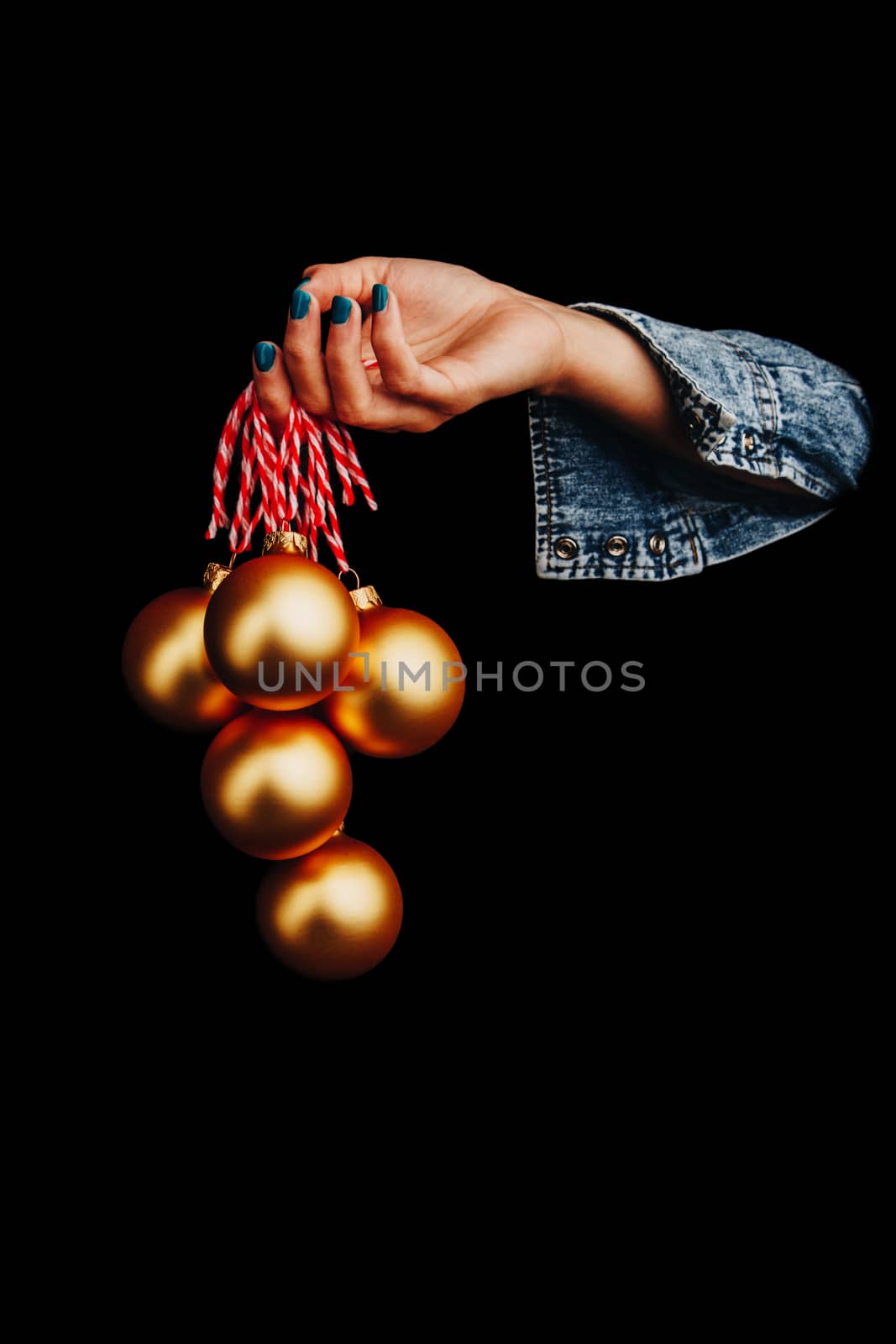 golden Christmas balls in woman's hand isolated on black background. new year card by yulaphotographer
