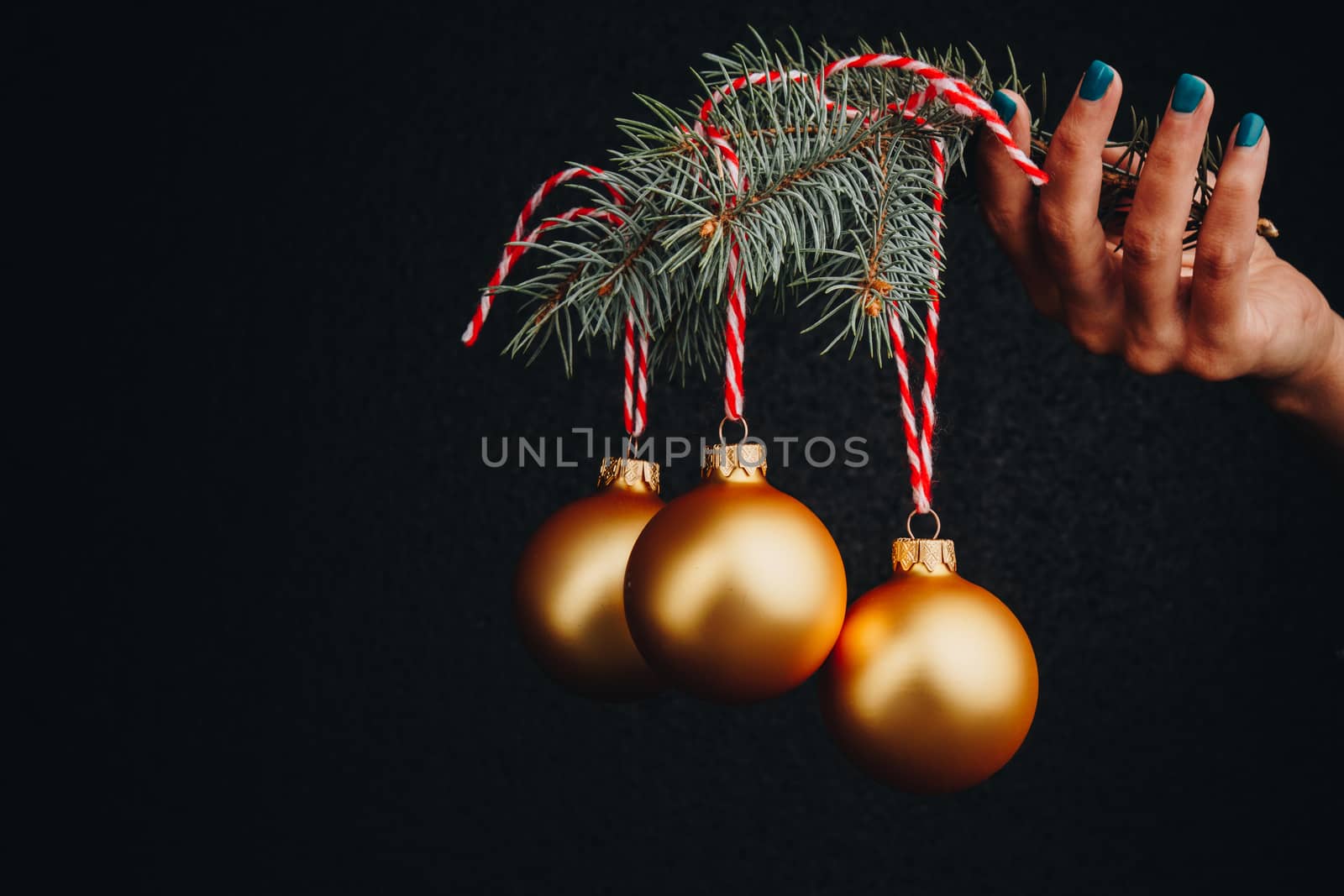 christmas and new year gift-card. branches of fir-tree and decoration with golden balls with red thread on a black background isolated close up by yulaphotographer