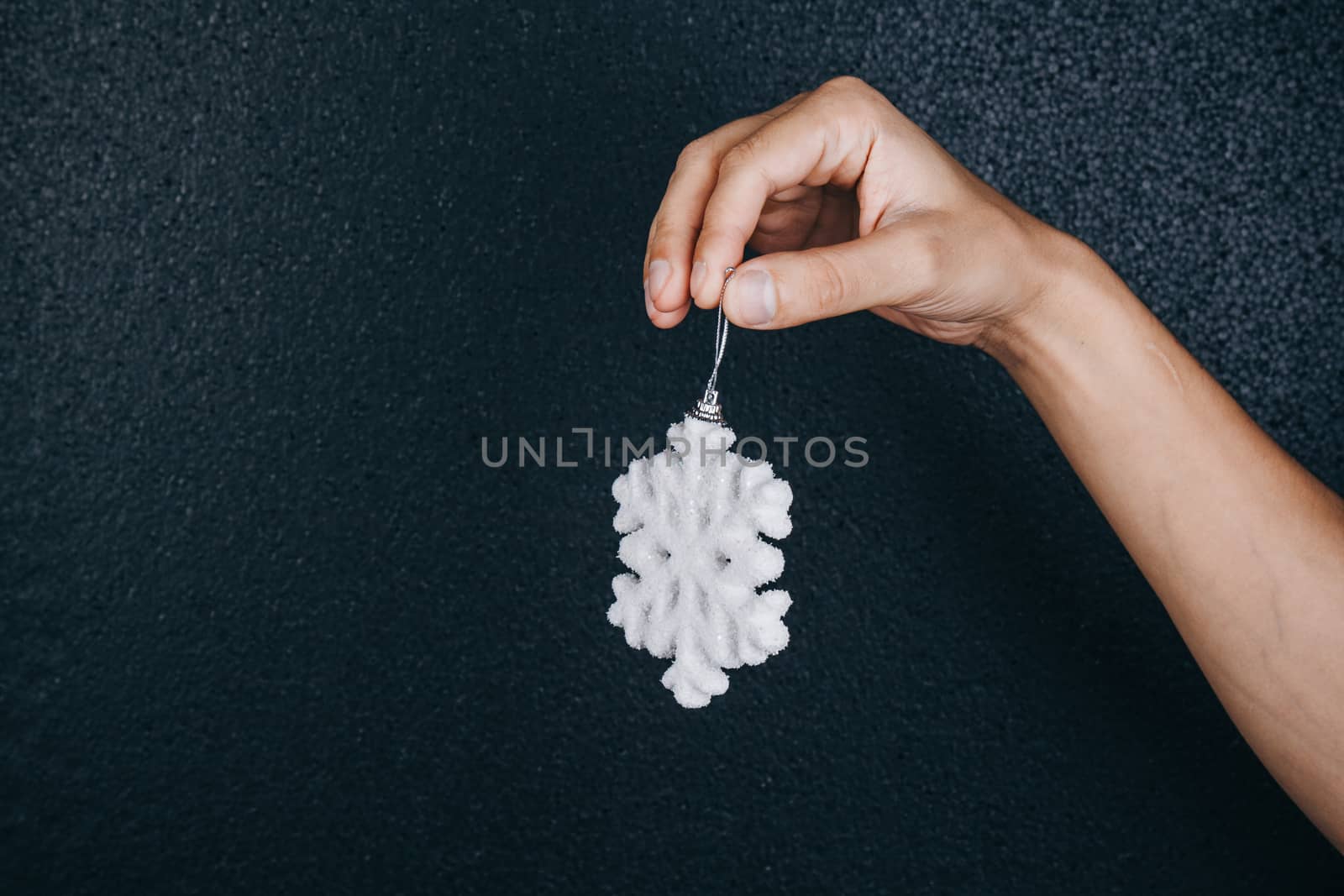 woman hand holding hanging snowflake toy for christmas decoration isolated on black background. new year gift card. handmade by yulaphotographer