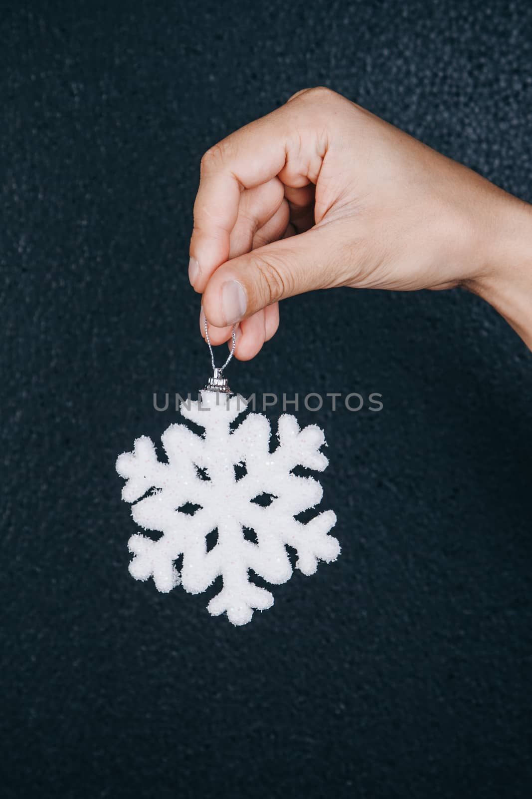 woman hand holding hanging snowflake toy for christmas decoration isolated on black background. new year gift card. handmade by yulaphotographer