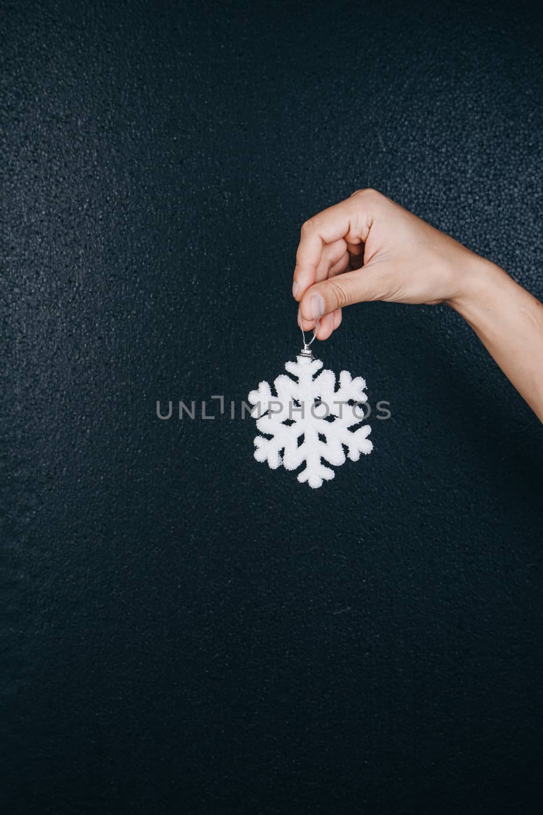 woman hand holding hanging snowflake toy for christmas decoration isolated on black background. new year gift card.