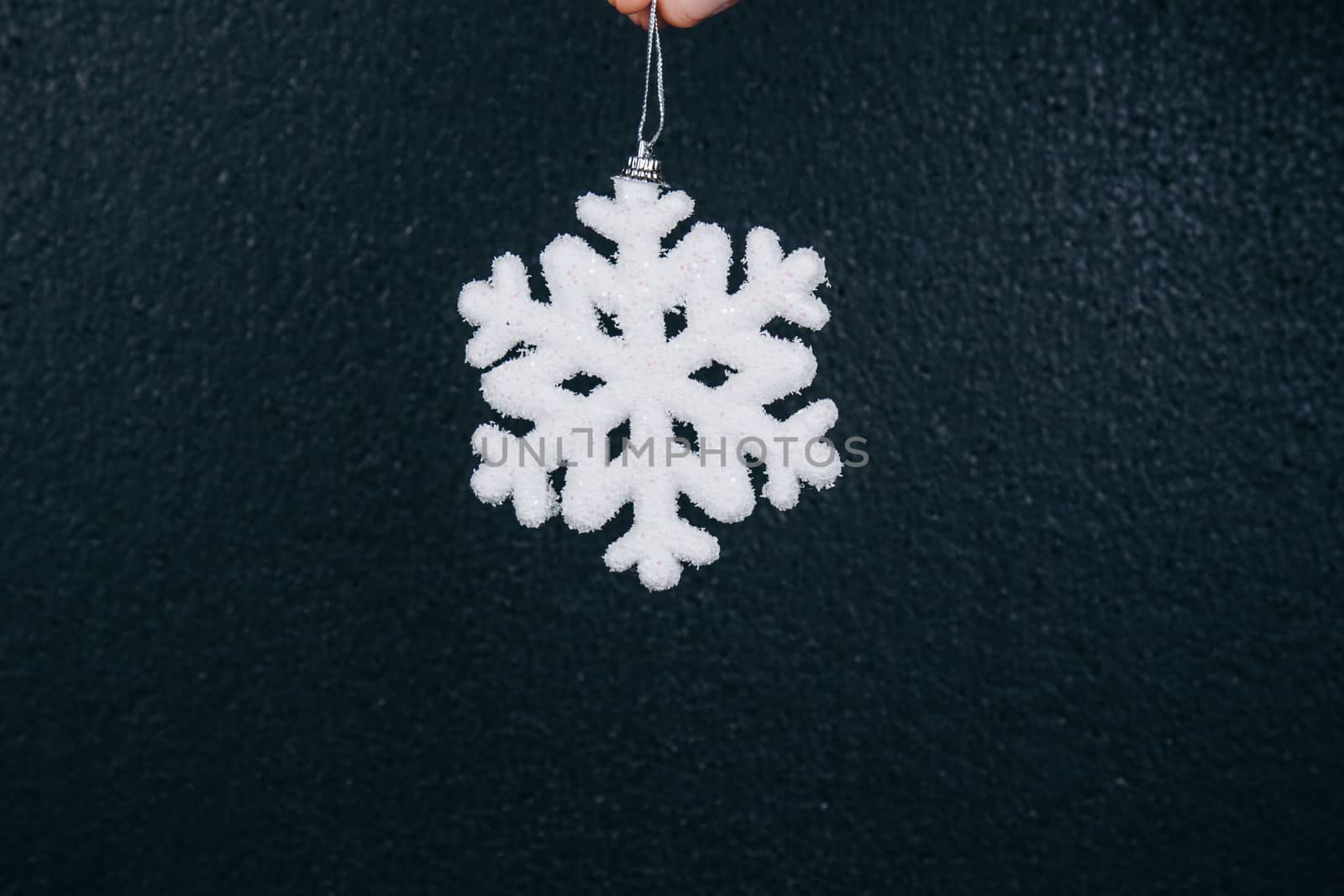 woman hand holding hanging snowflake toy for christmas decoration isolated on black background. new year gift card.
