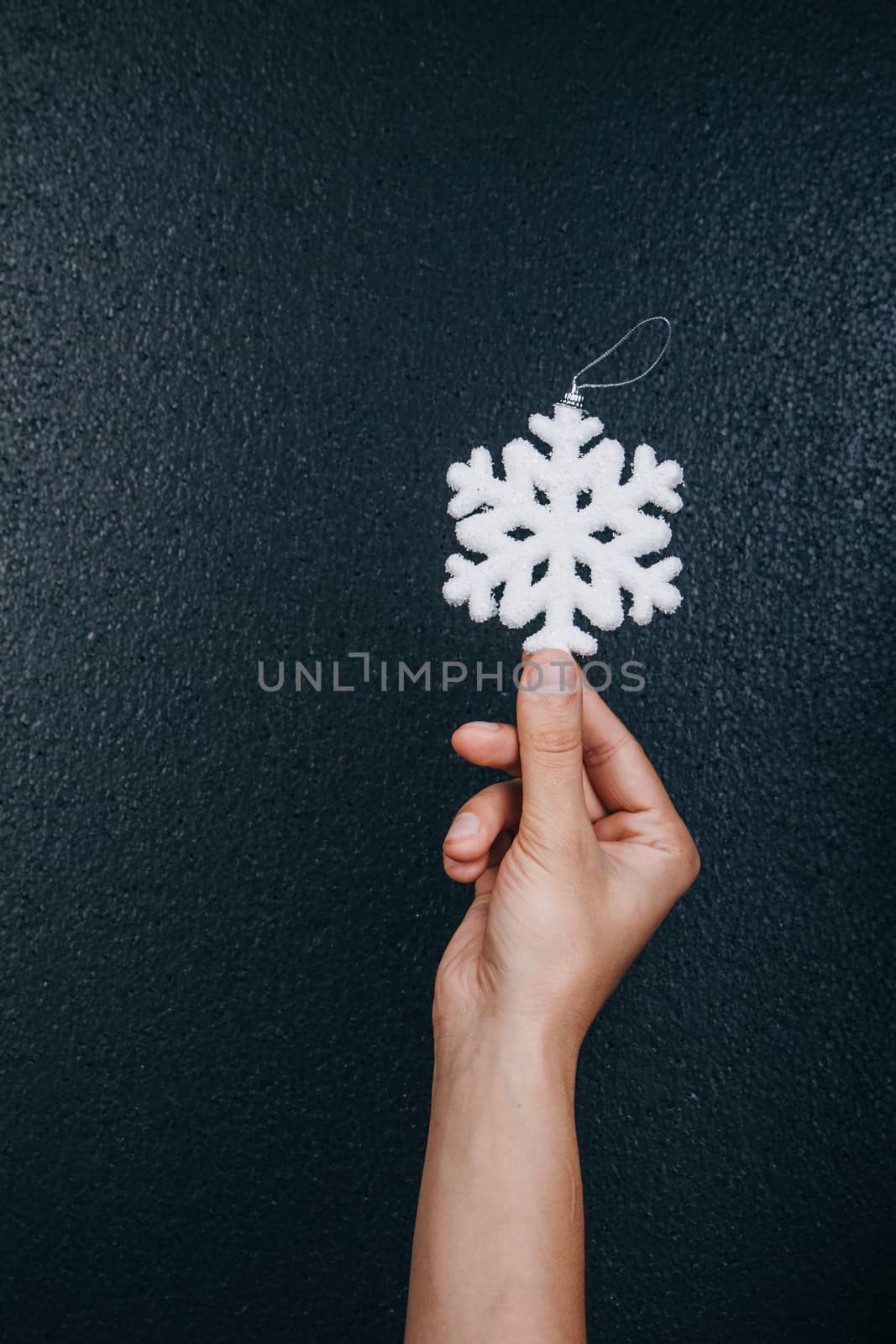 woman hand holding hanging snowflake toy for christmas decoration isolated on black background. new year gift card.