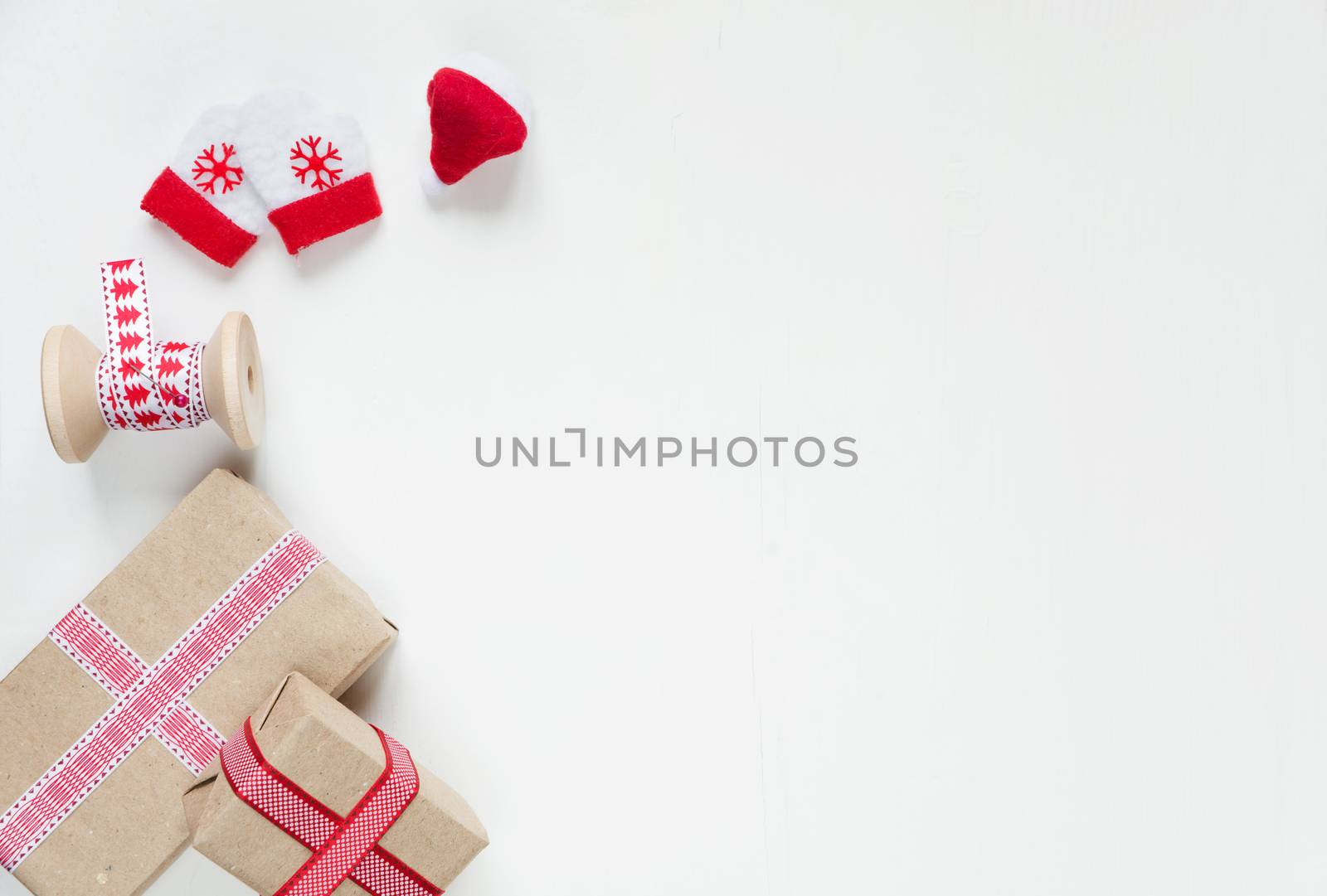Red Christmas frame, consisting of gift boxes tied with ribbons, Santa's glove and mittens on a white background with space for text. Flat lay composition for greeting cards, websites, social media, magazines, bloggers, artists etc. Christmas wallpaper