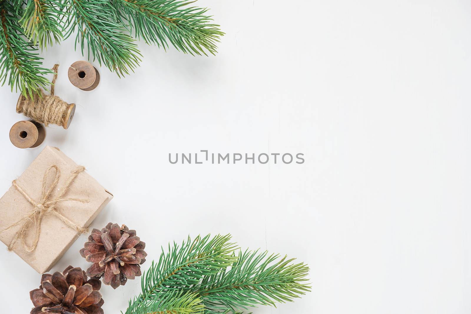 Christmas frame, consisting of fir branches, cones and gift boxe tied with hemp twine on a white background with space for text. Flat lay composition for greeting cards, websites, social media, magazines, bloggers, artists etc. Christmas wallpaper