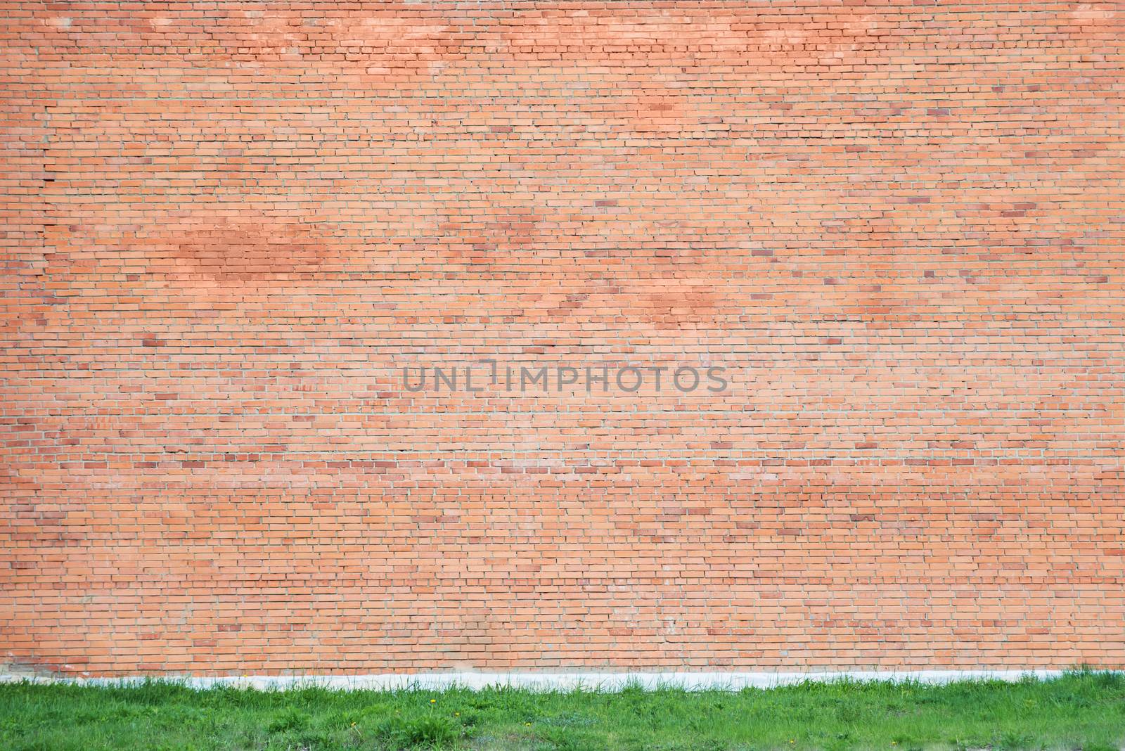 Large wall of red brick with a border of green grass