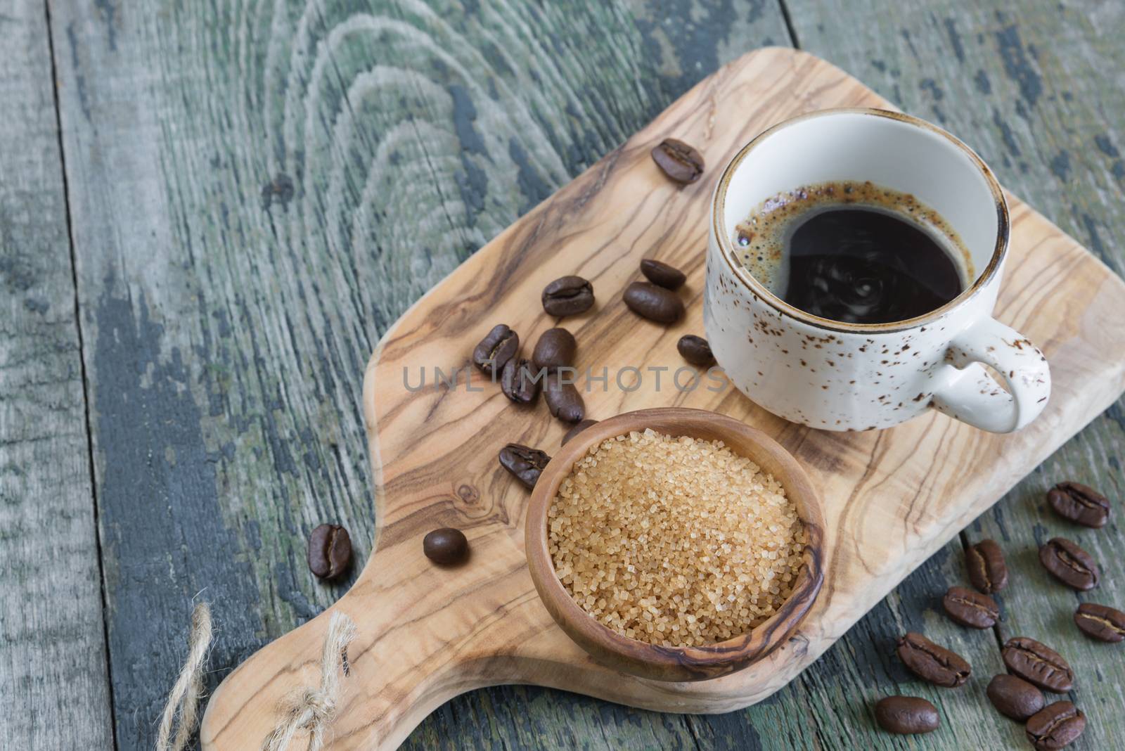 Black coffee in old coffee cup spilled coffee beans and cane sugar in a wooden bowl on the old wooden table