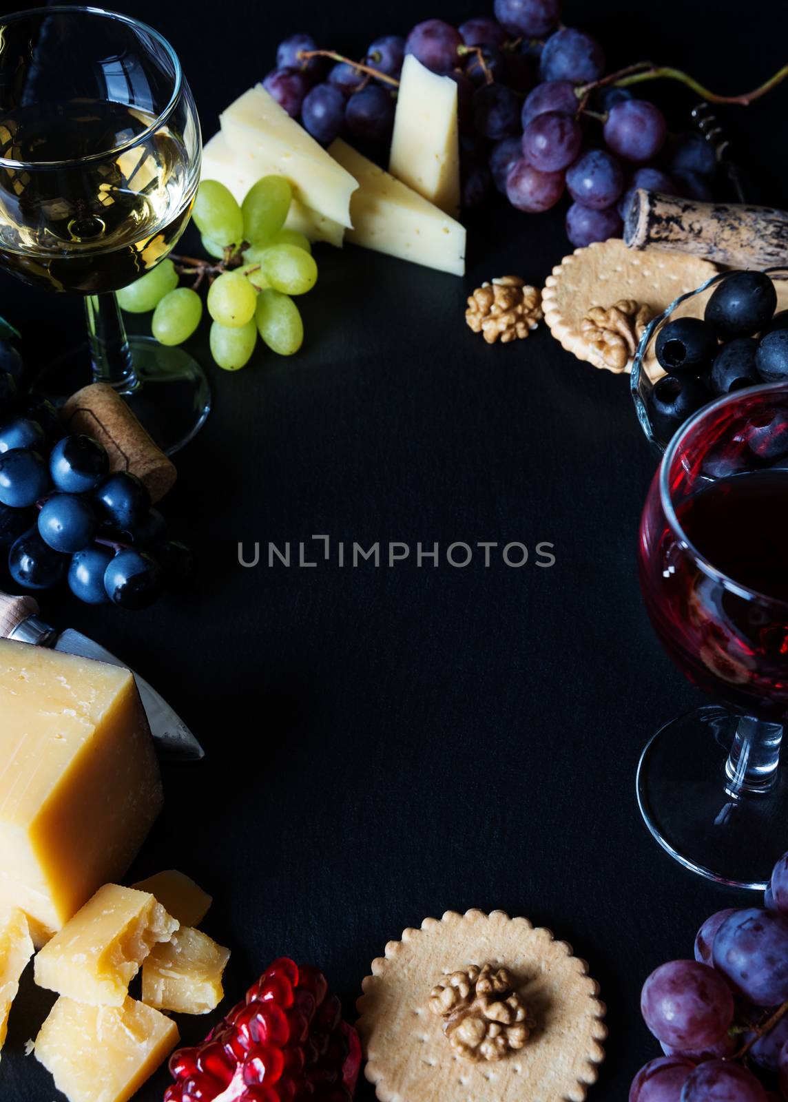 Wine and snacks arranged in the form of a border on a black background